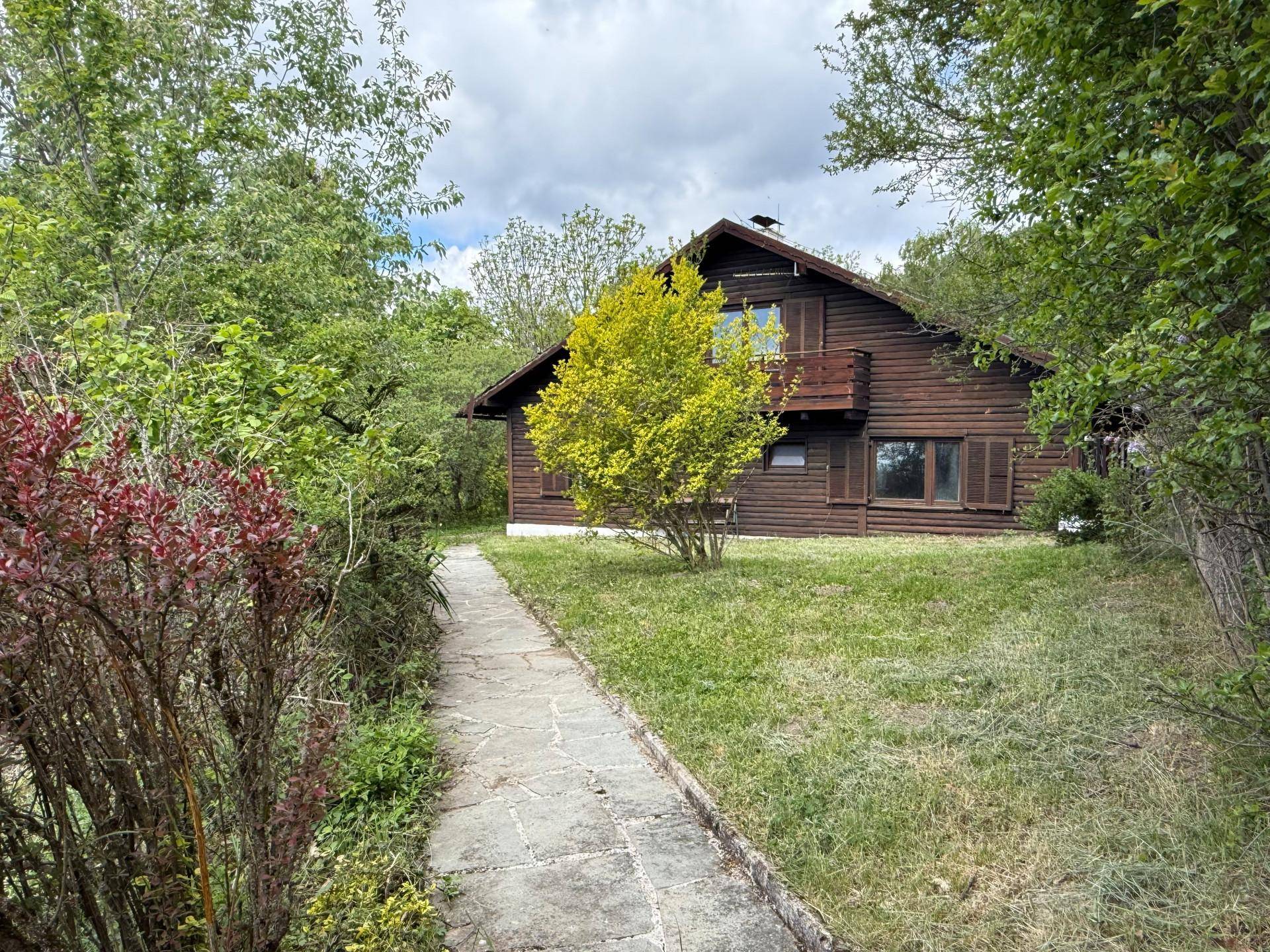 Charmantes Holzhaus mit Balkon, umgeben von einem gepflegten Garten und einem Steinweg.