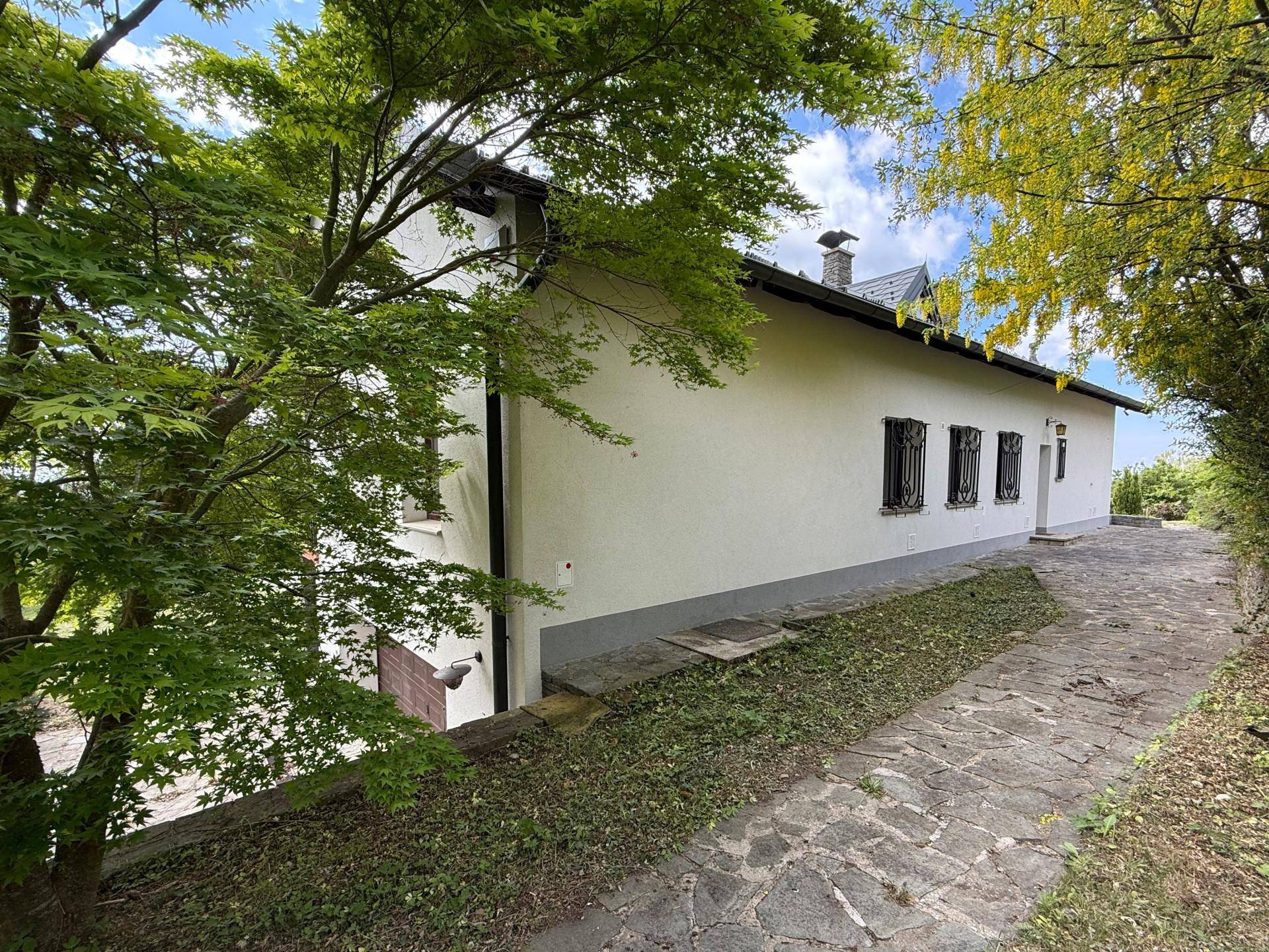 Lange Steinweg führt entlang der weißen Hausfassade mit vergitterten Fenstern und üppigem Grün.