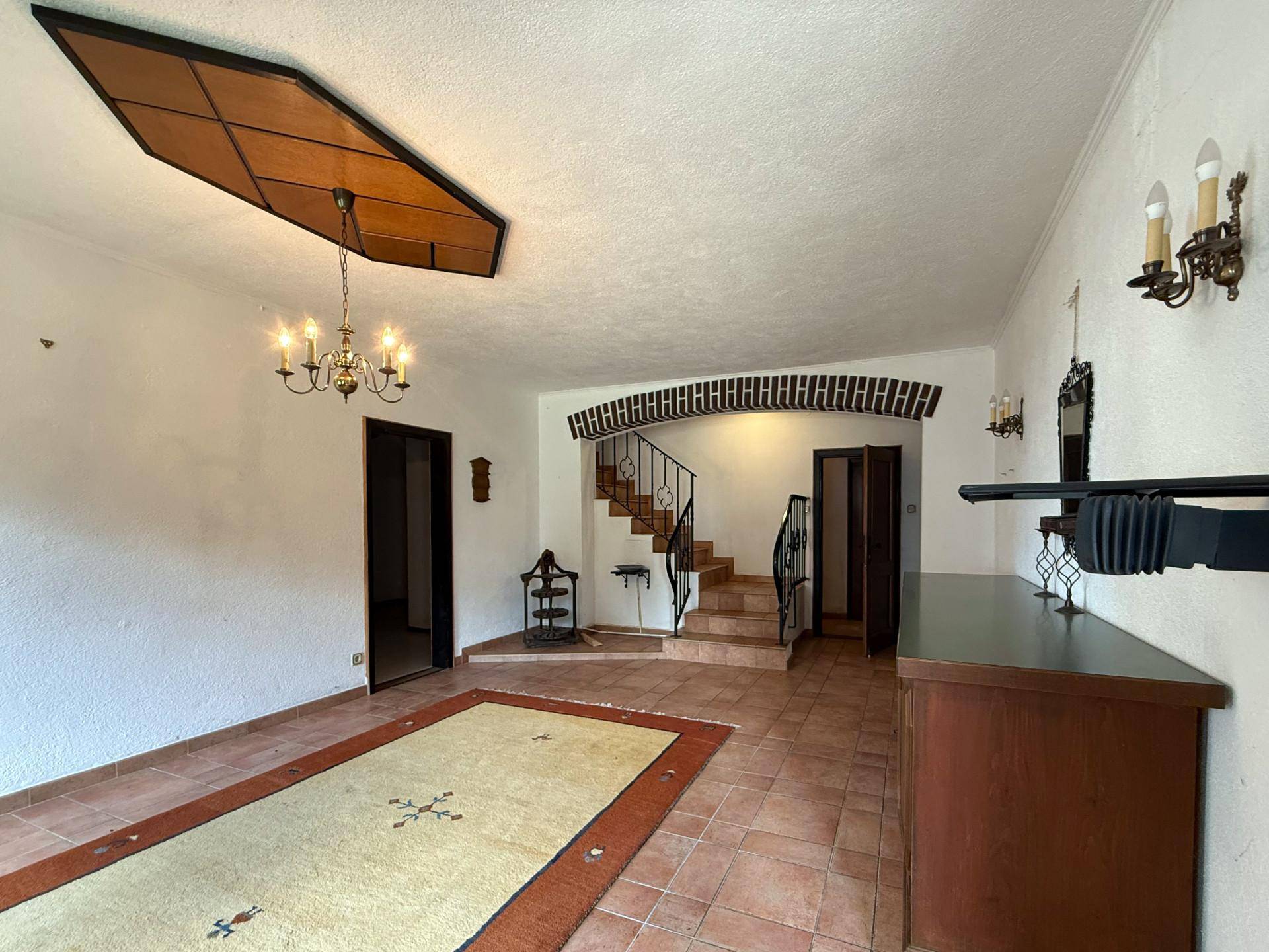 Geräumiger Flur mit Terrakotta-Fliesenboden, einer geschwungenen Treppe und traditionellen Wandleuchten.