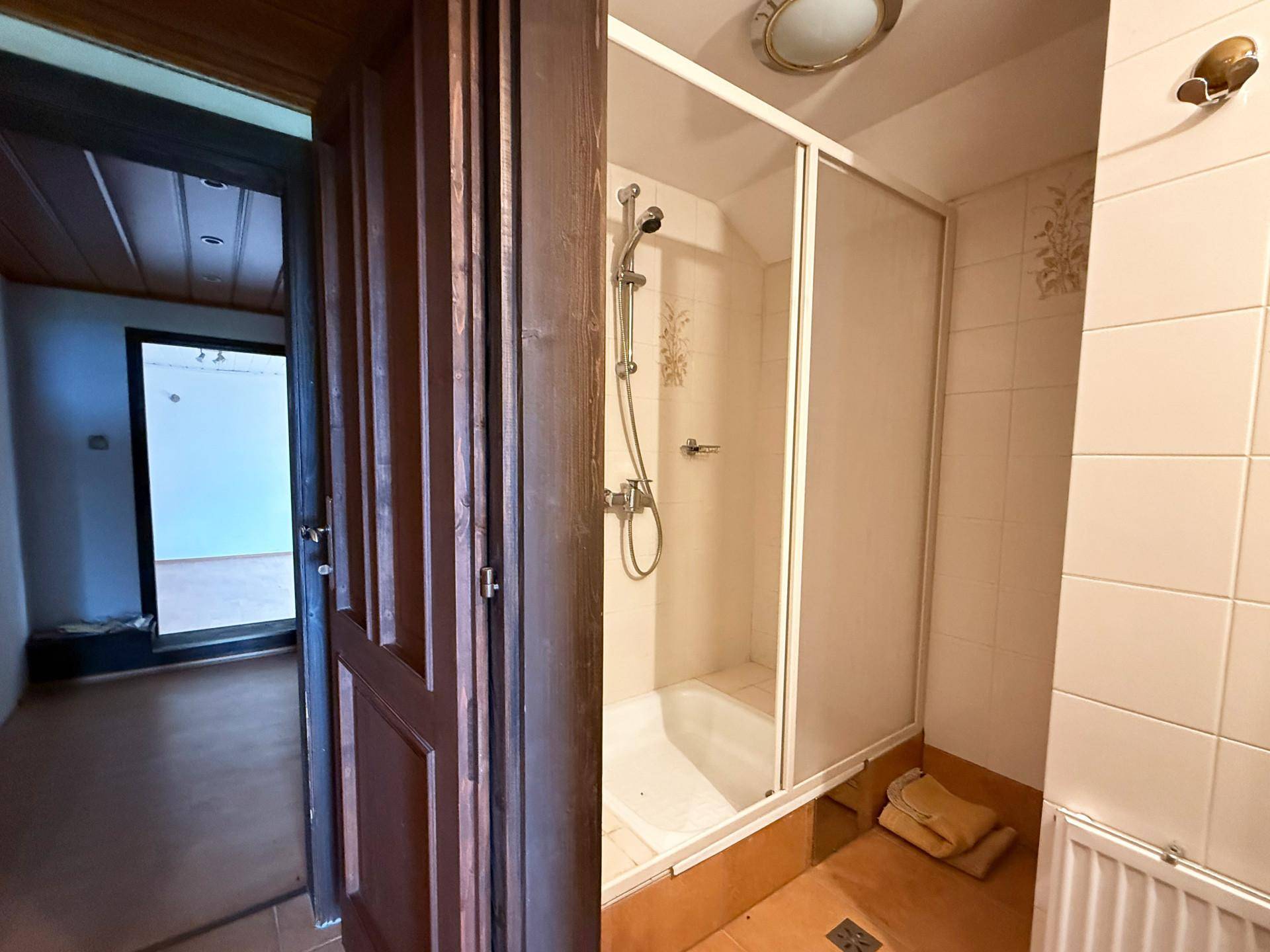 Kleines Badezimmer mit Duschkabine, gefliesten Wänden und Boden in warmen Farbtönen.
