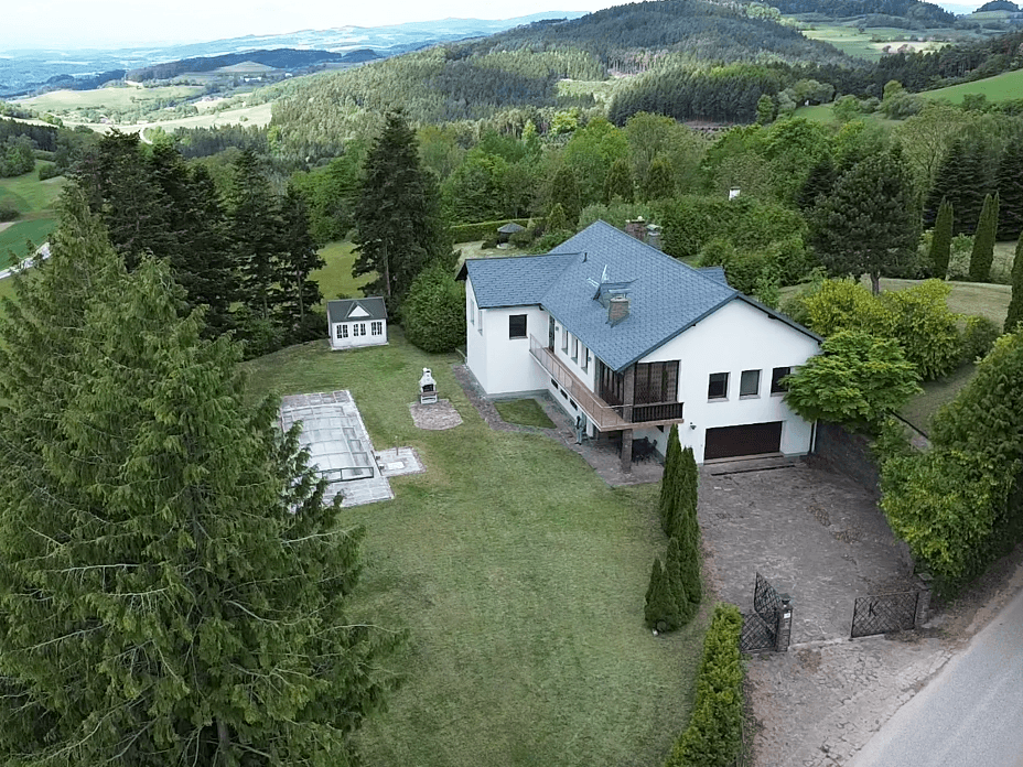 Luftaufnahme eines Hauses mit großem Garten, Poolbereich und weitem Blick über die Landschaft.