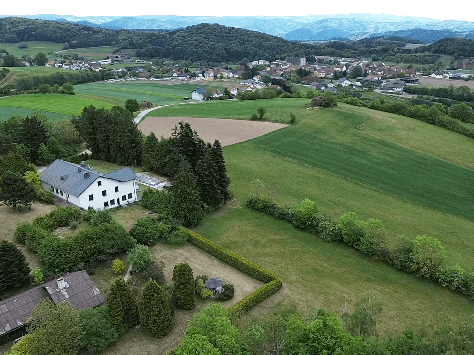 Luftaufnahme des Anwesens mit Blick auf ein entferntes Dorf und die hügelige Landschaft.