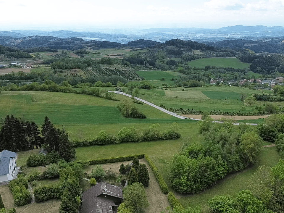 Weitläufige Landschaftsaufnahme mit grünen Hügeln, Feldern und einem Panoramablick.