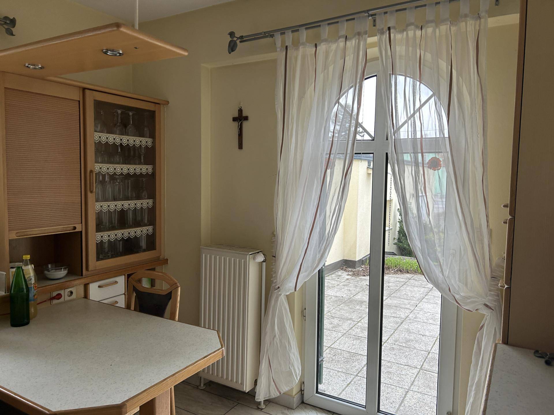 Essbereich in der Küche mit Zugang zu einer gepflasterten Terrasse im Freien.