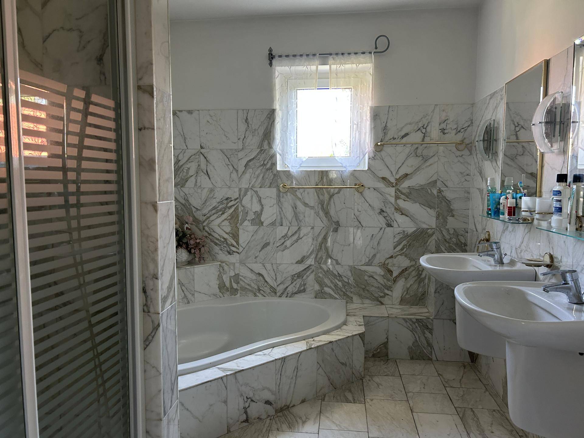 Marmorbadezimmer mit Doppelwaschbecken, Badewanne und separater Duschkabine.