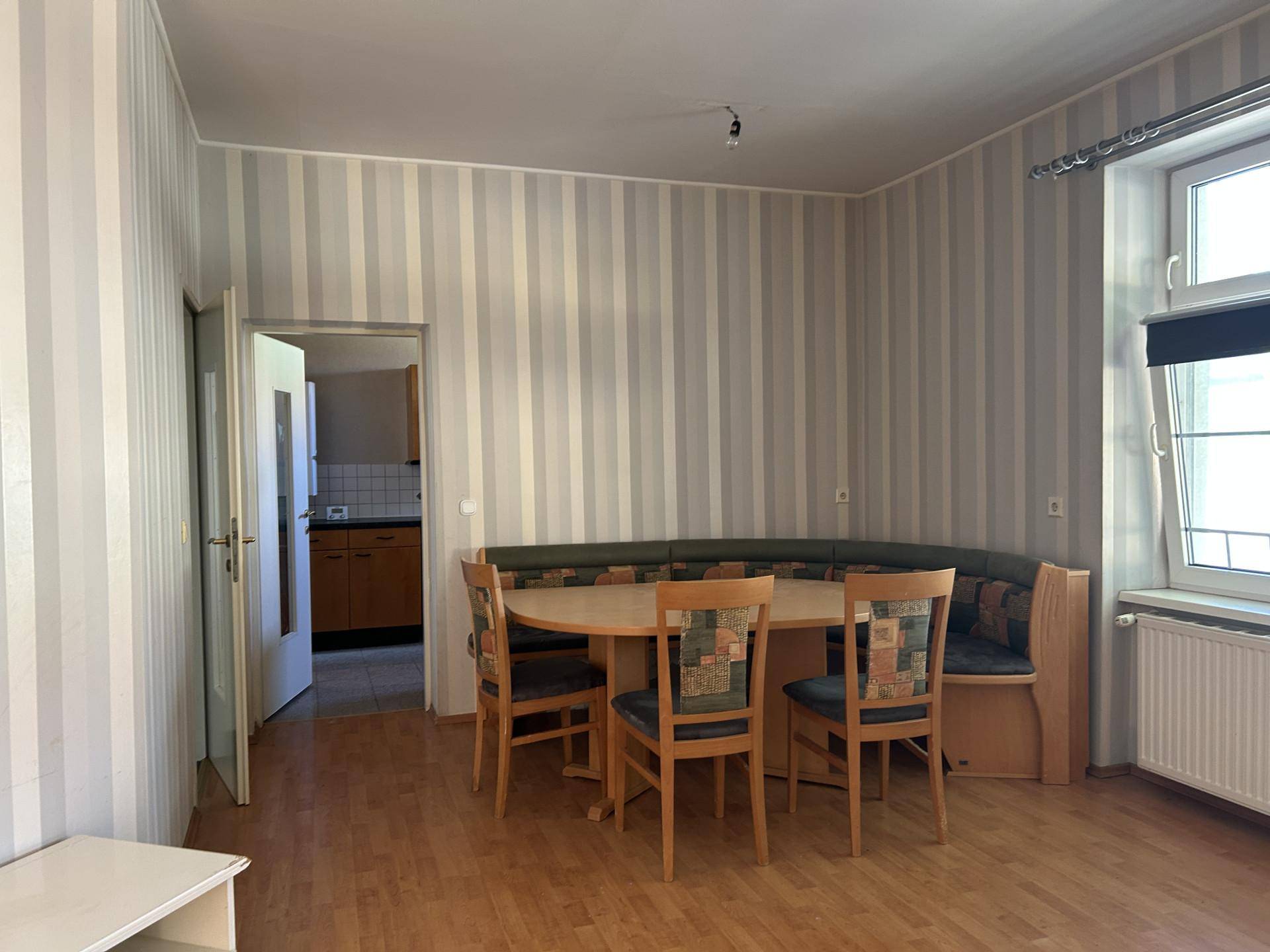 Esszimmer mit gestreifter Tapete, Eckbank und Holzboden.