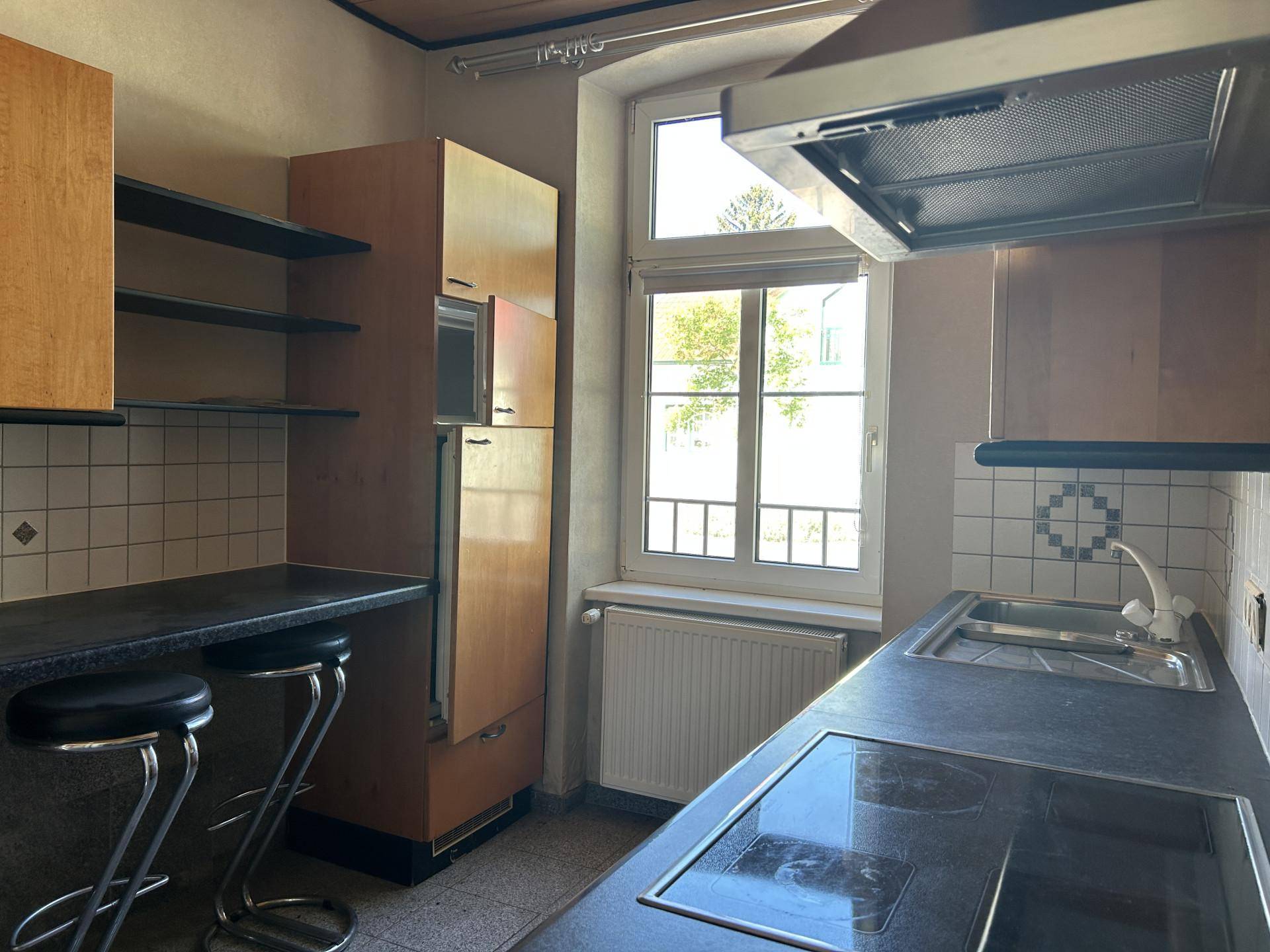 Funktionale Küche mit dunklen Arbeitsplatten, Kochfeld und integriertem Kühlschrank.