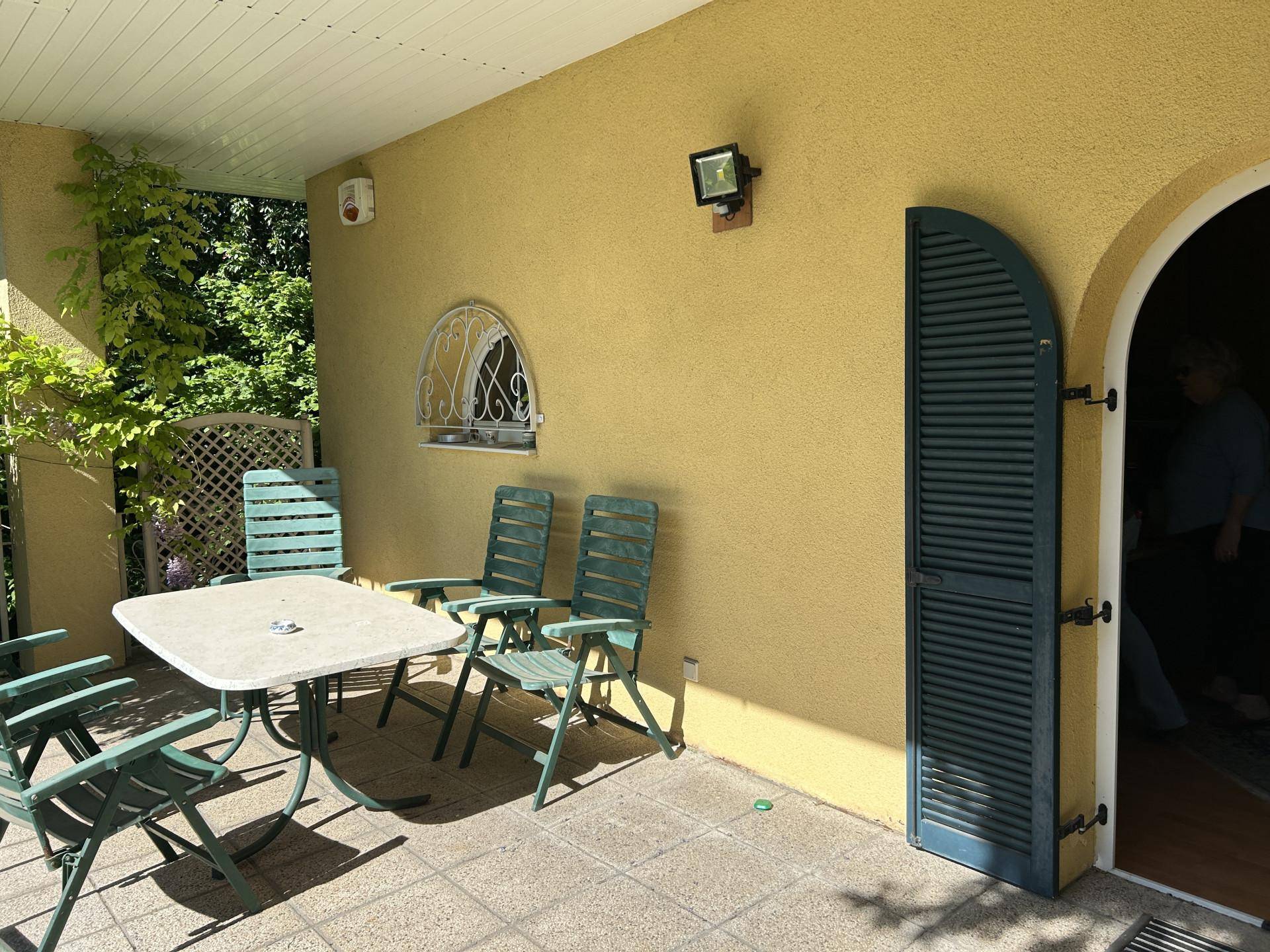 Überdachte Terrasse mit Gartenmöbeln und Blick auf die grüne Umgebung.