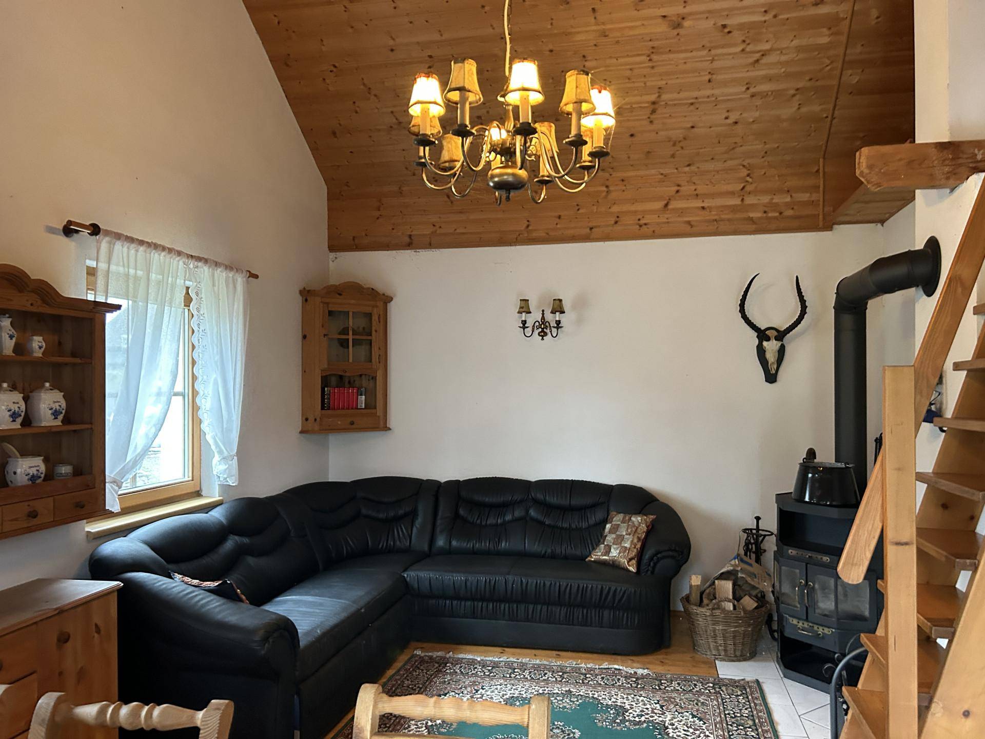 Gemütliches Wohnzimmer mit Holzbalkendecke, Kaminofen und traditioneller Dekoration.