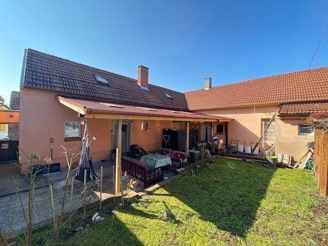 Hinterhof mit überdachter Terrasse, Rasenfläche und Blick auf das traditionelle Ziegeldach.