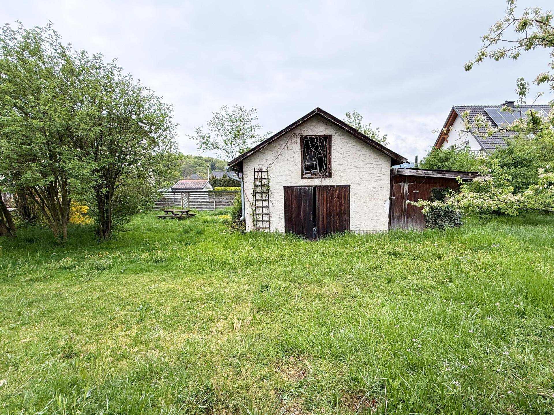 Nebengebäude mit Holztüren und großem Garten, der viel Platz für Gestaltung bietet.
