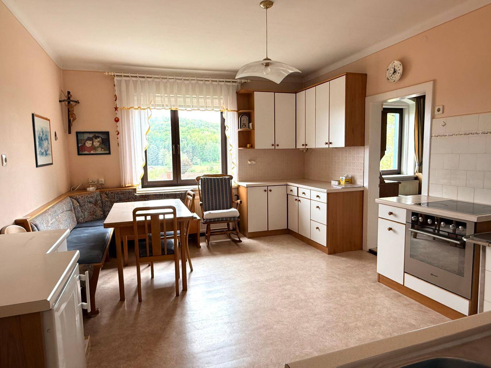 Gemütliche Wohnküche mit Essecke, Holzmöbeln und einem Fenster mit Blick ins Grüne.