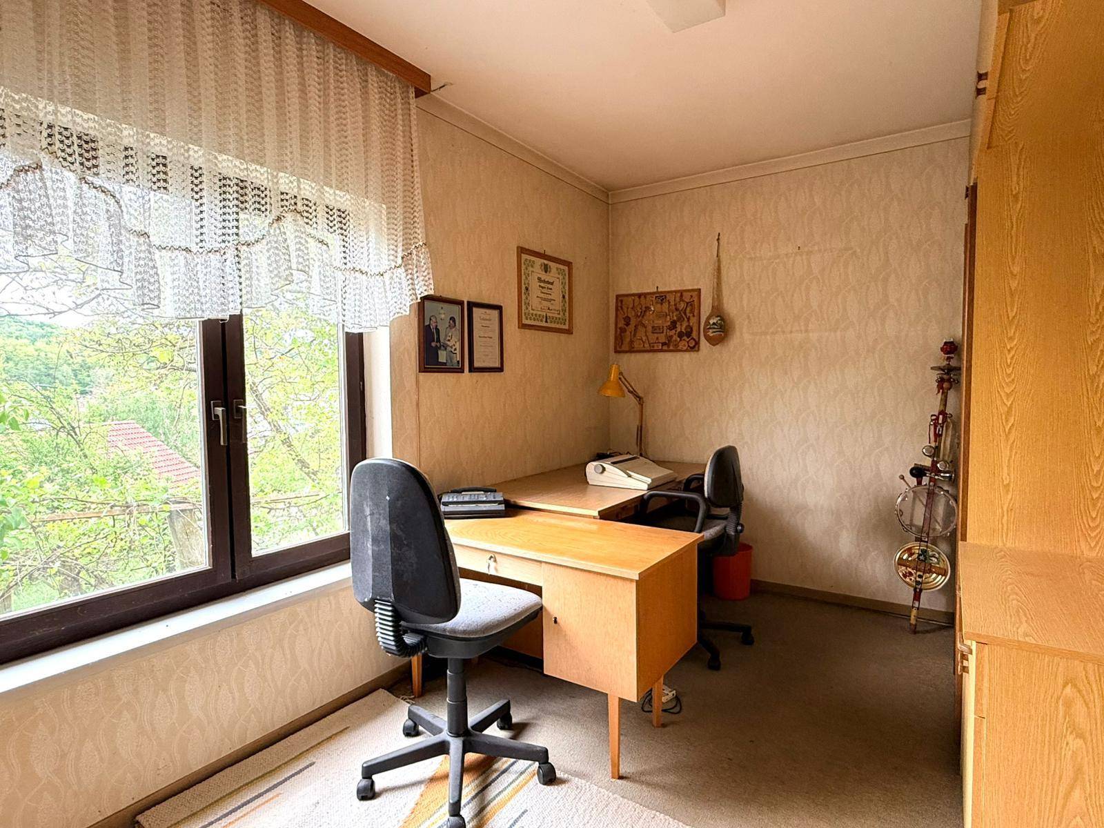 Helles Arbeitszimmer mit zwei Schreibtischen, Bürostühlen und einem großen Fenster.