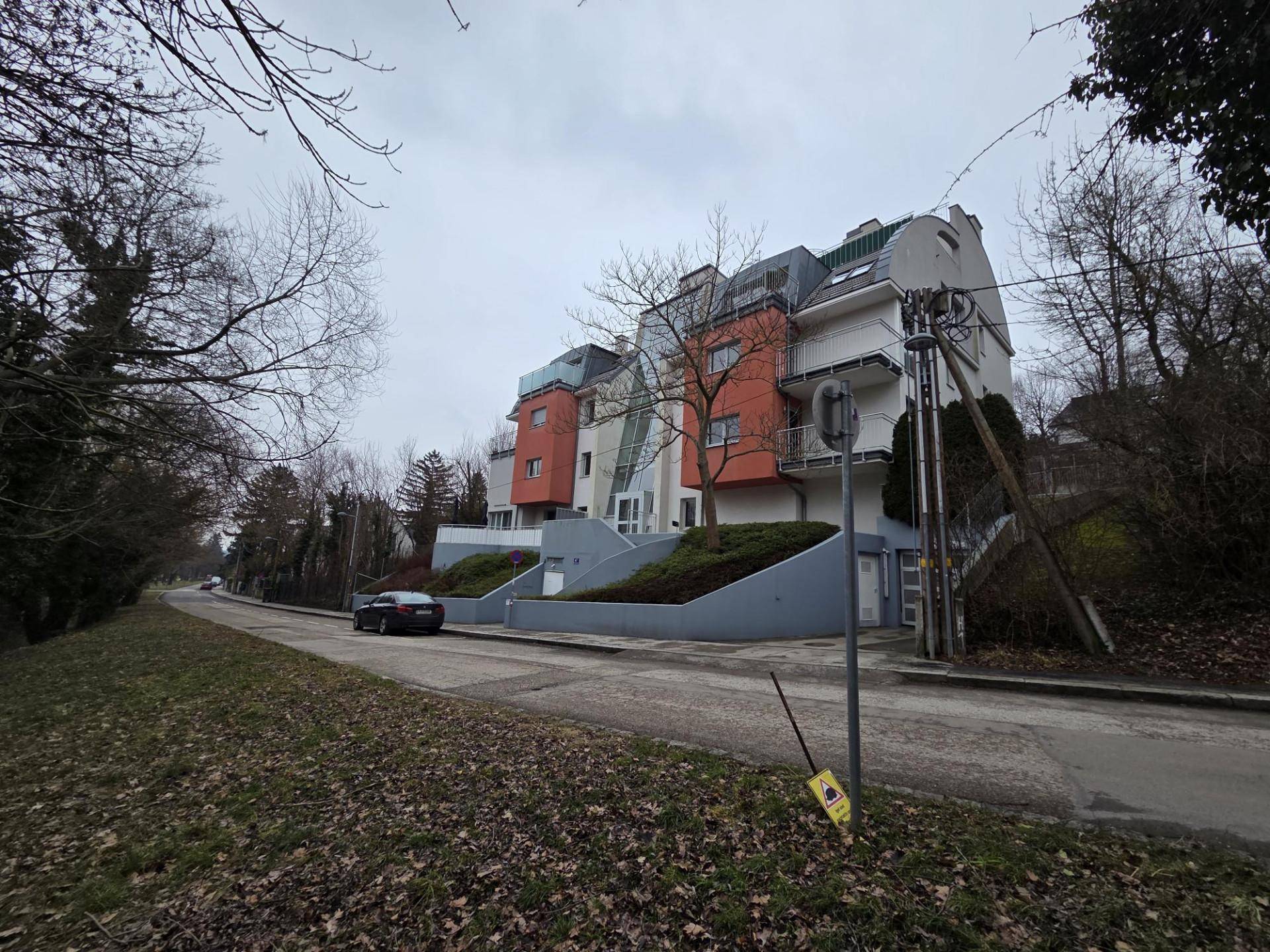 Wohngebäude mit moderner Architektur, umgeben von Bäumen und einer ruhigen Straße.