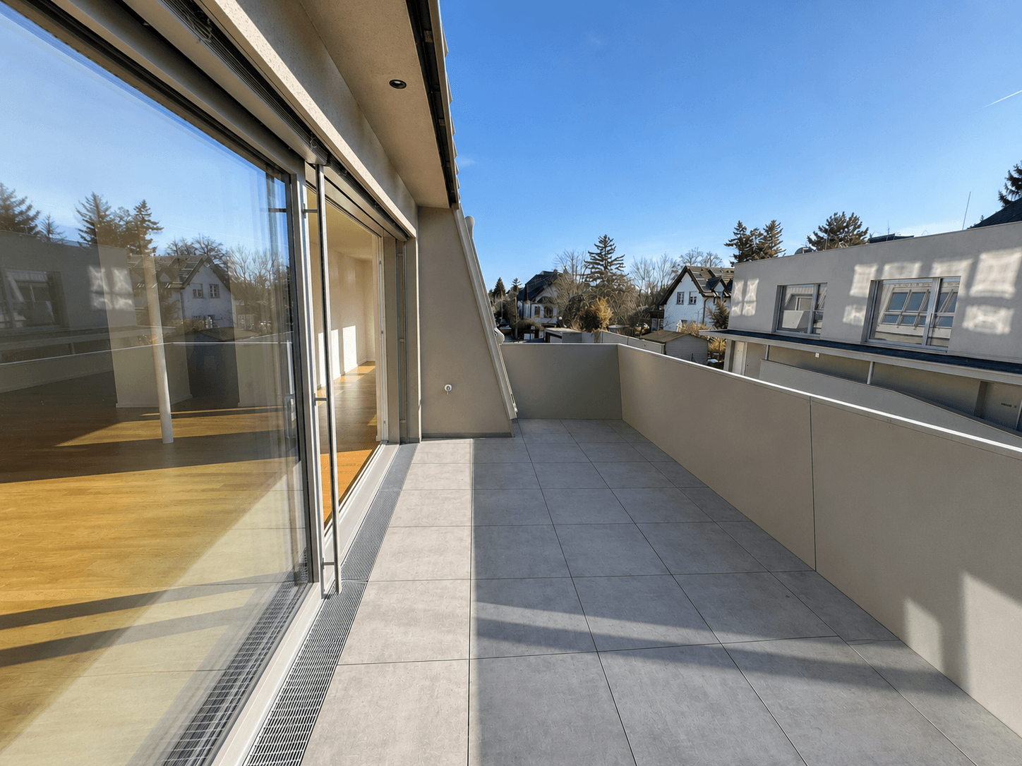 Geräumige Terrasse mit Fliesenboden, niedriger Brüstung und weitem Blick auf die Umgebung.