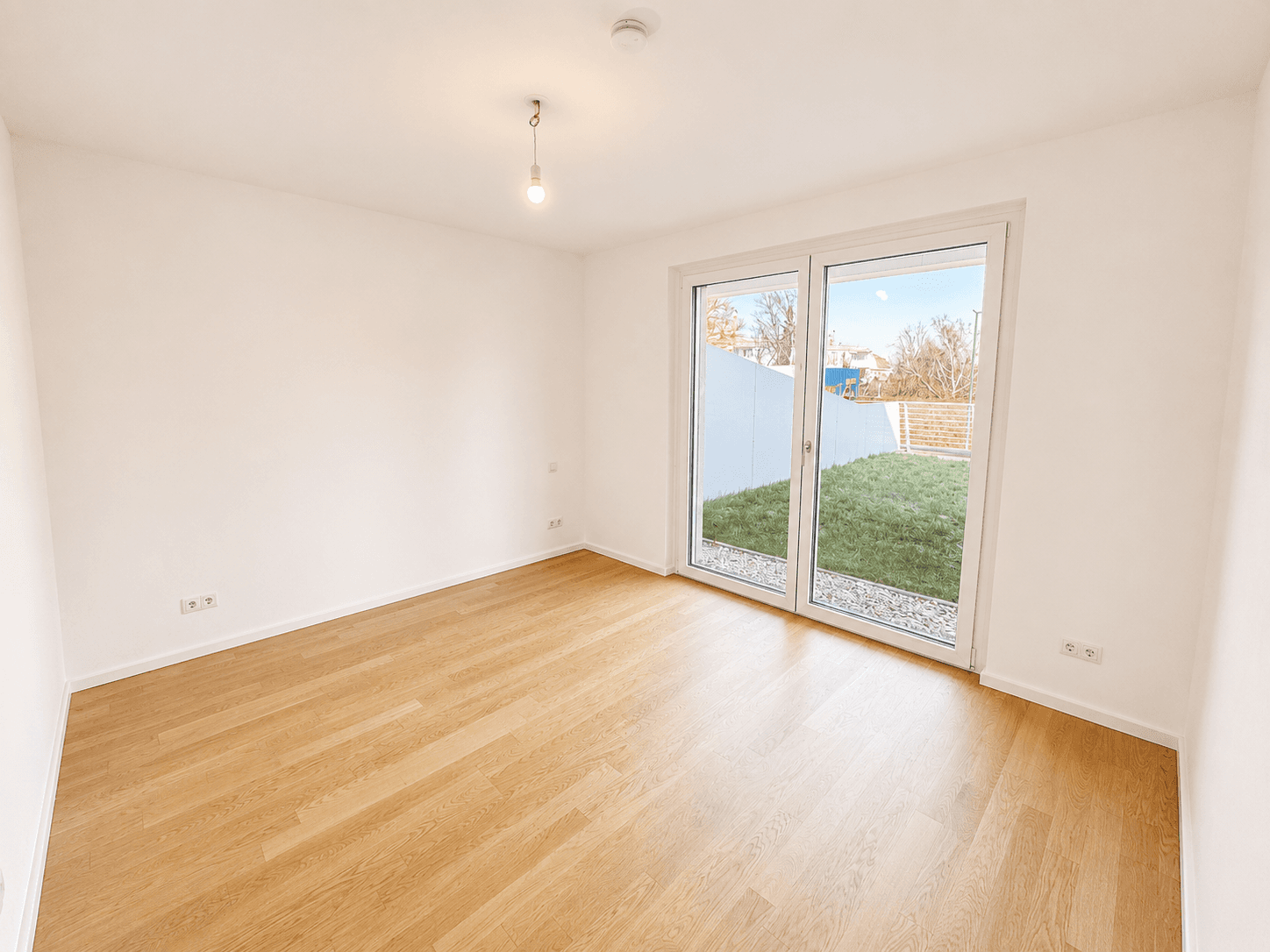 Helles Schlafzimmer mit Holzboden und Zugang zu einem kleinen privaten Gartenbereich.