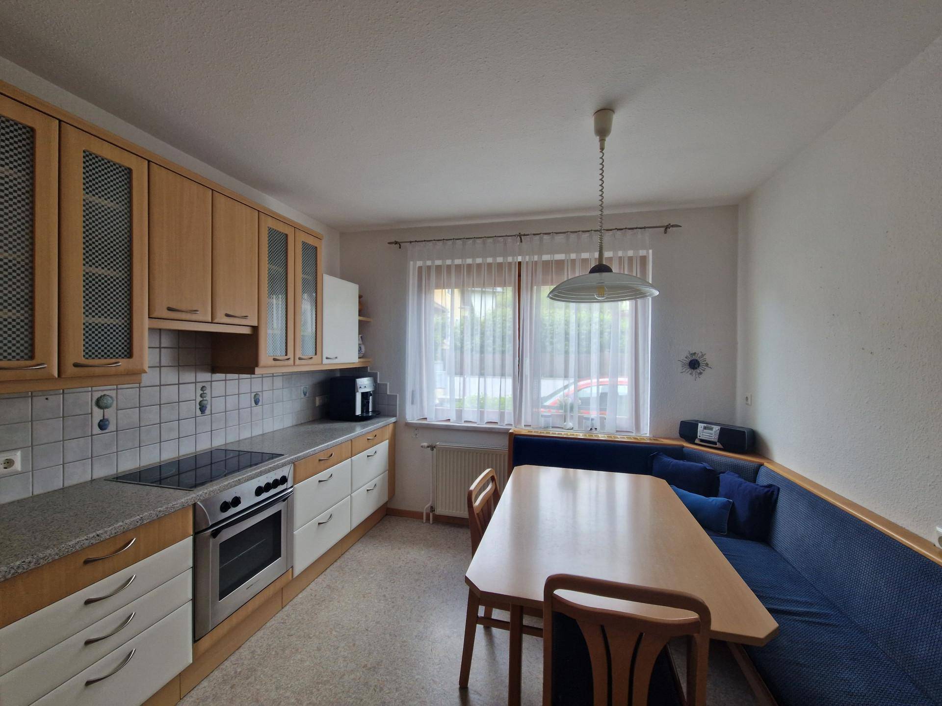 Funktionale Küche mit Essbereich, blauer Sitzbank und Fenster für natürliches Licht.