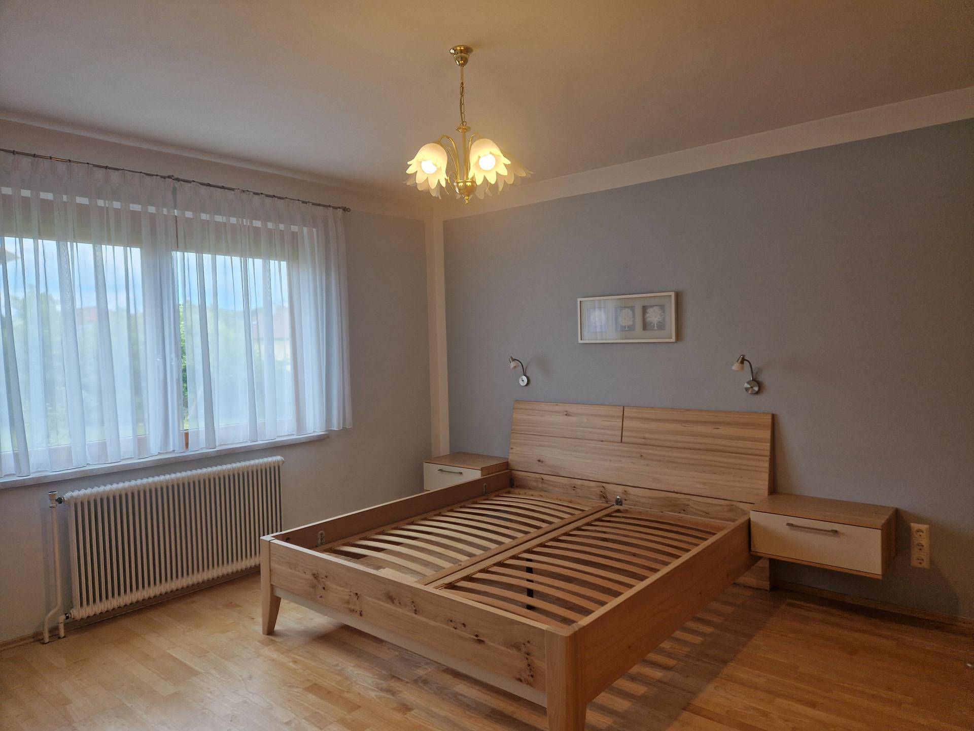 Helles Schlafzimmer mit Holzbett, Parkettboden und großem Fenster für viel Licht.