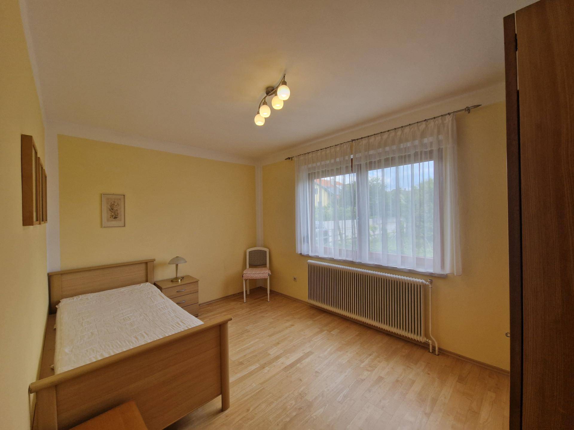 Gemütliches Schlafzimmer mit Einzelbett, Parkettboden und großem Fenster.