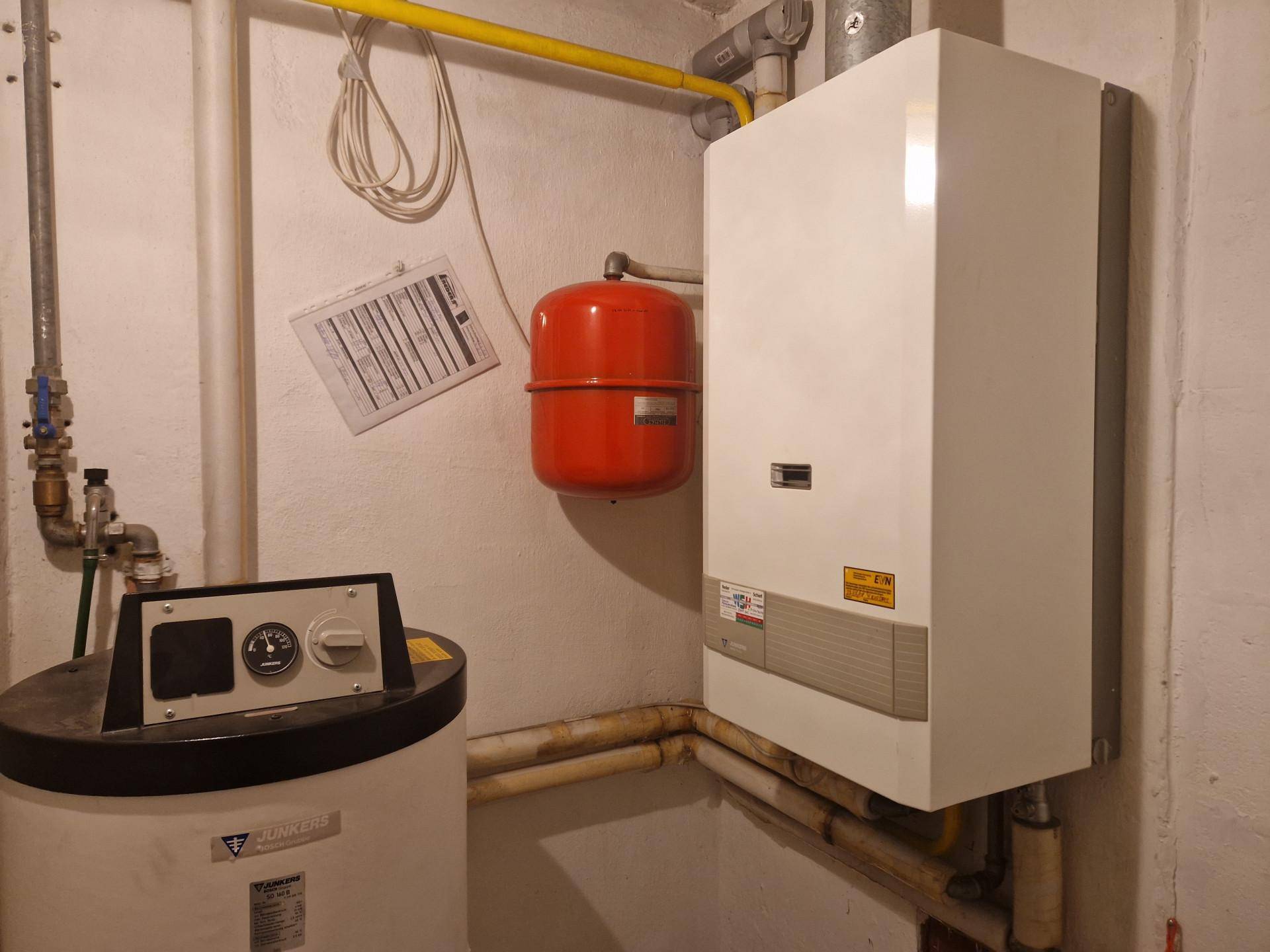 Heizungsraum im Keller mit moderner Heizungsanlage und Warmwasserspeicher.