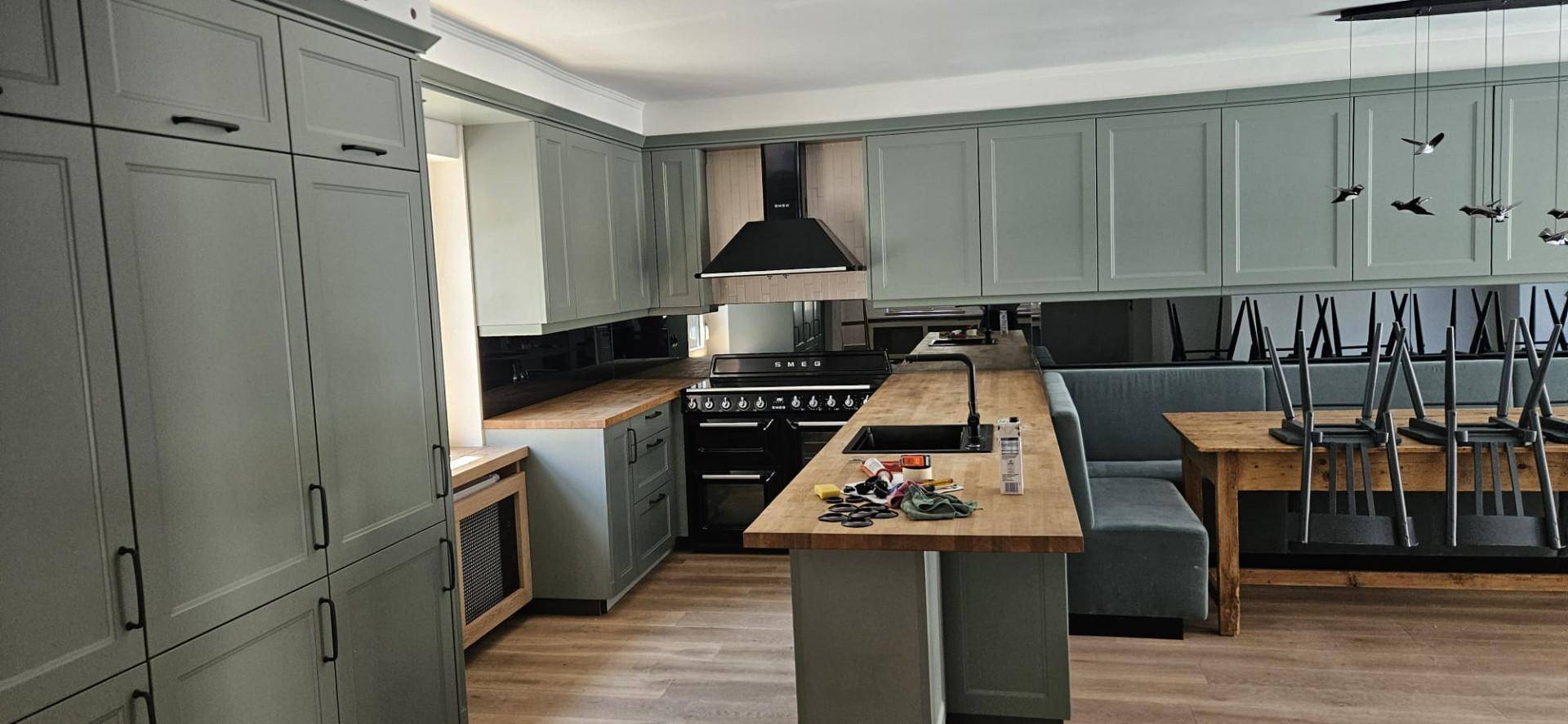 Geräumige Küche in Grün mit Holztheke, modernen Geräten und Essbereich.