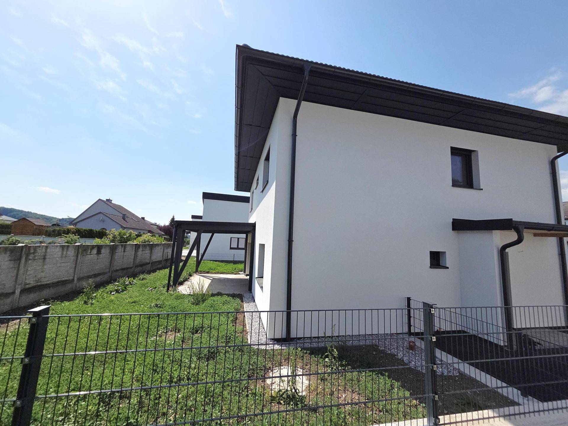 Rückseite eines modernen Hauses mit überdachter Terrasse und angrenzendem Gartenbereich.