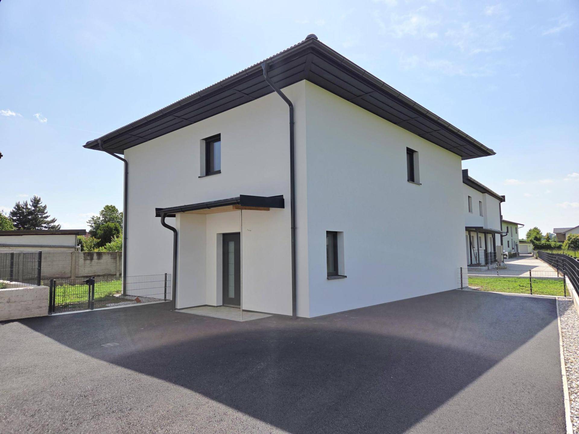 Vorderansicht eines modernen Einfamilienhauses mit Zufahrt und überdachtem Eingangsbereich.