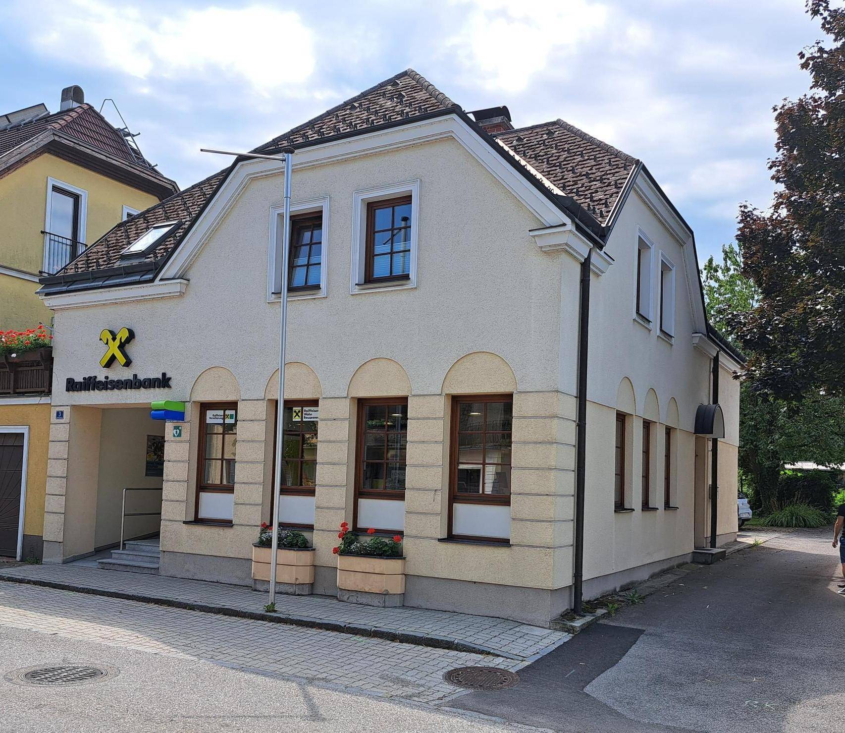 Seitenansicht des Bankgebäudes mit Fenstern, Satteldach und klassischer Architektur.