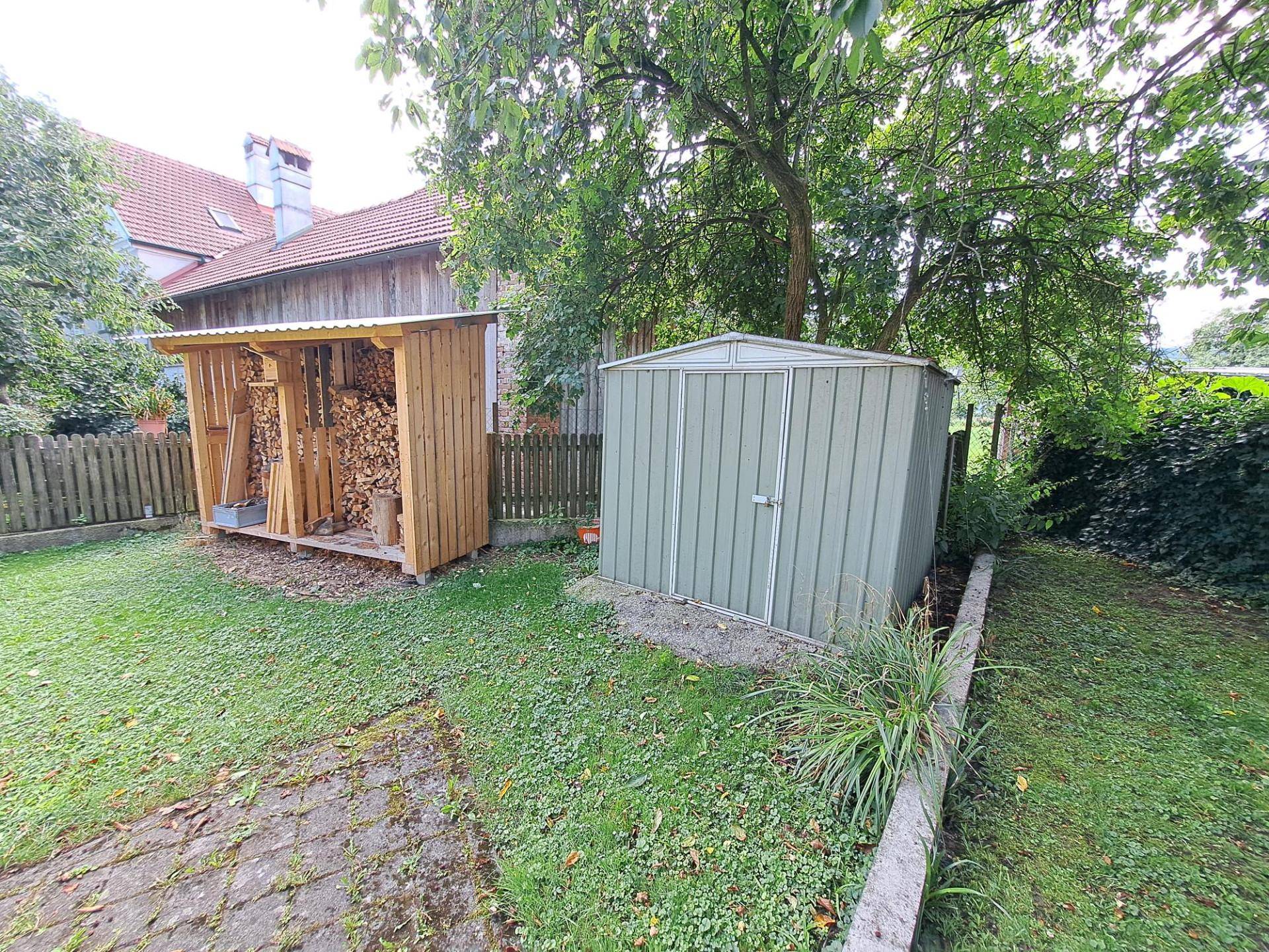 Gartenbereich mit einem Geräteschuppen und einem überdachten Holzunterstand.