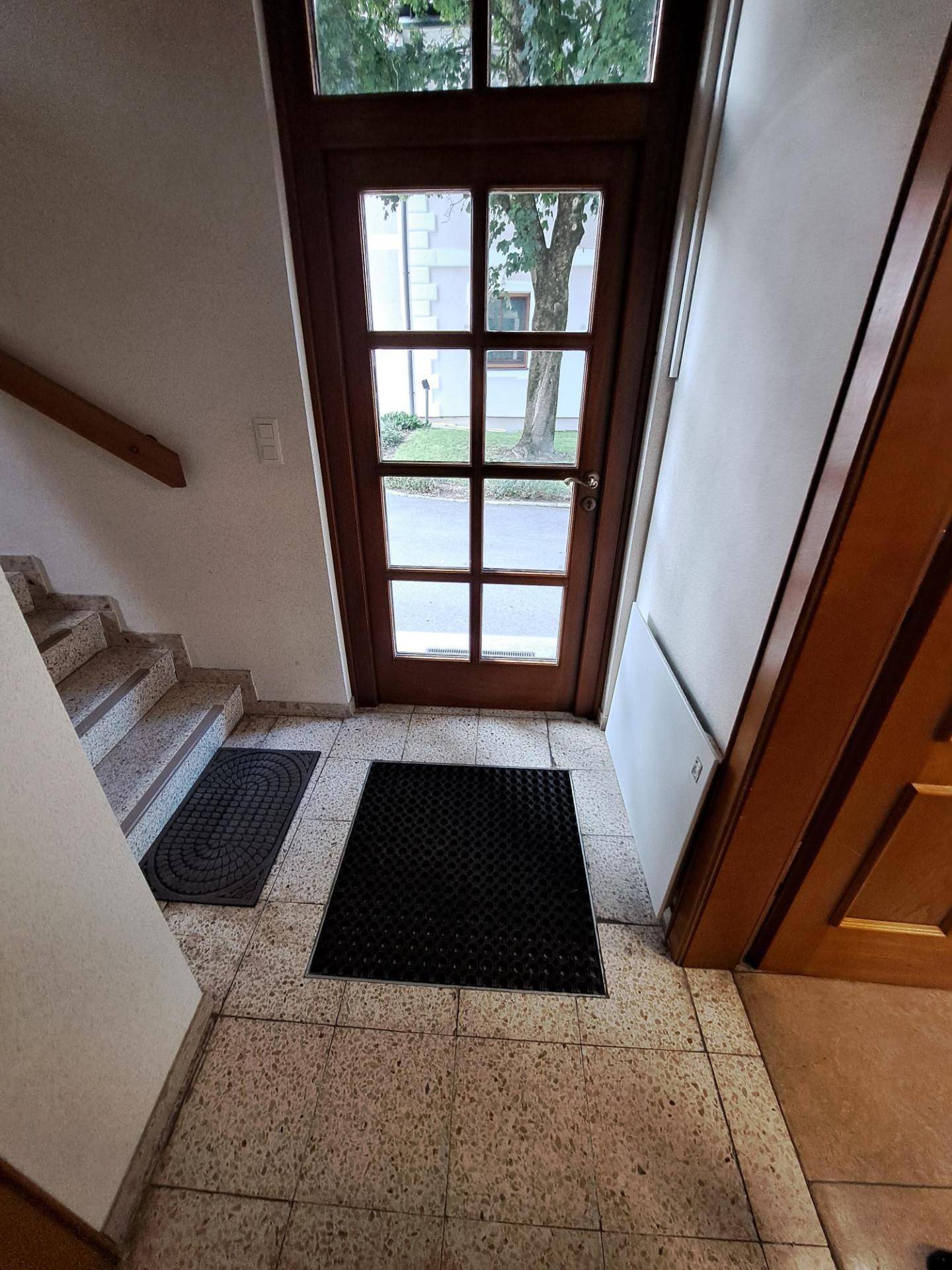 Eingangsbereich mit Fliesenboden, Holztür und Treppe zum Obergeschoss, hell und einladend.