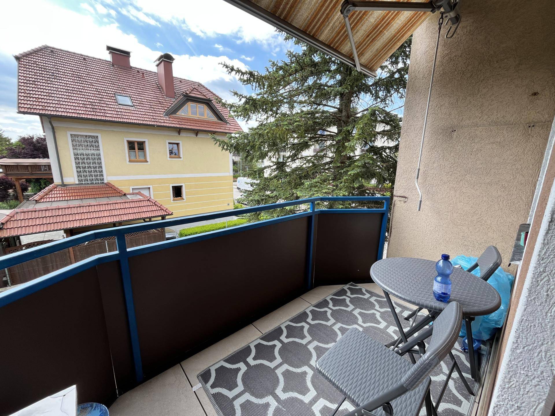 Gemütlicher Balkon mit Sitzgelegenheiten und Blick auf die umliegenden Häuser und Bäume.