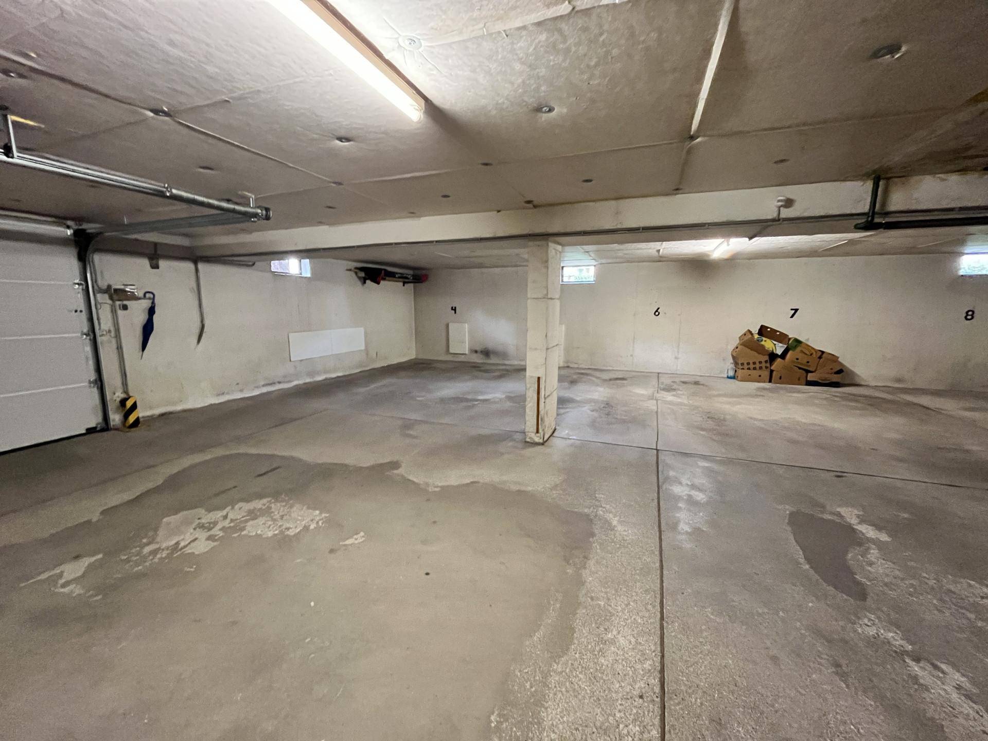 Leere Tiefgarage mit Betonboden und nummerierten Stellplätzen, bereit zur Nutzung.