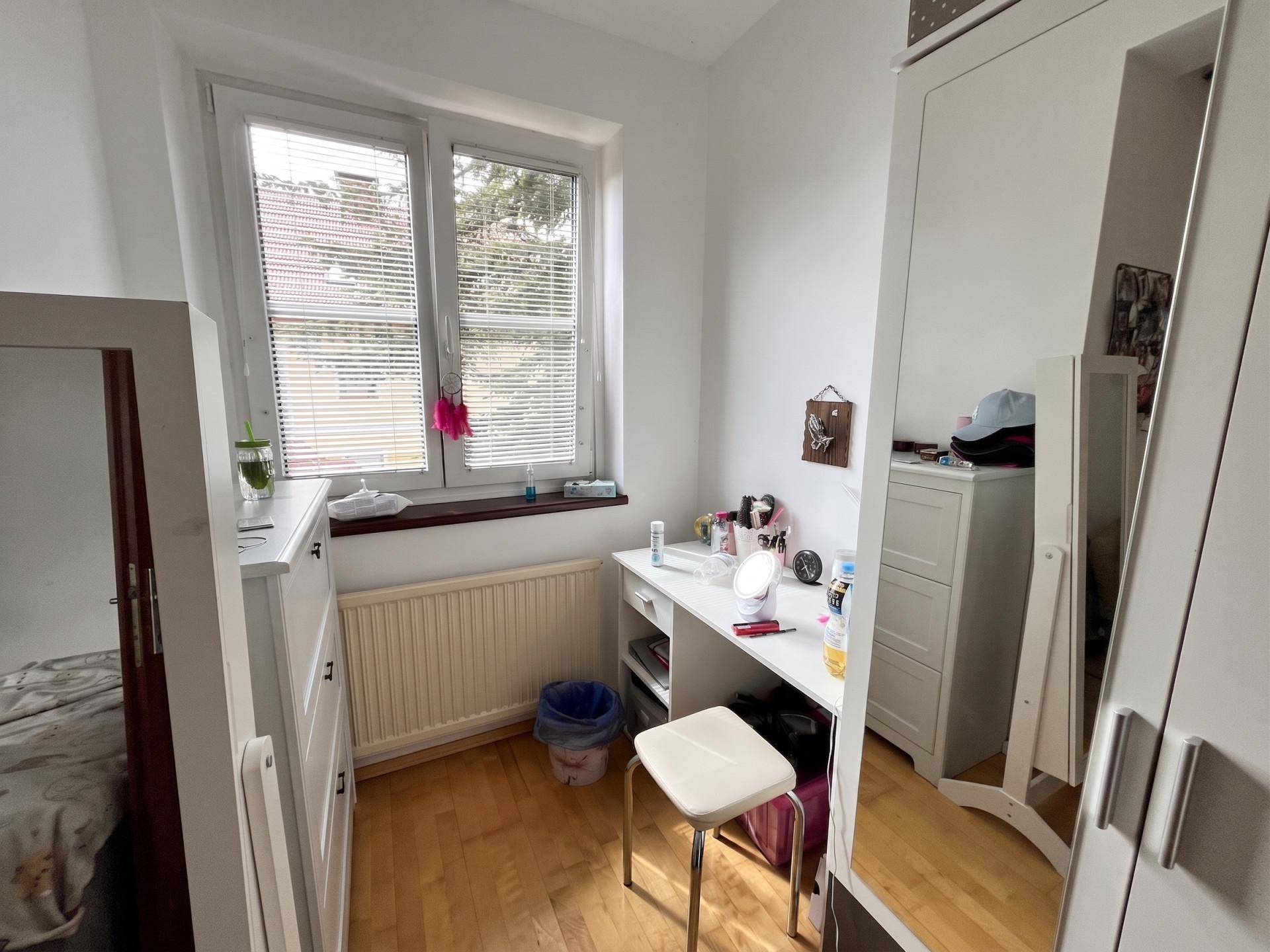 Helles Zimmer mit Schreibtisch, weißem Kleiderschrank und großem Fenster für Tageslicht.