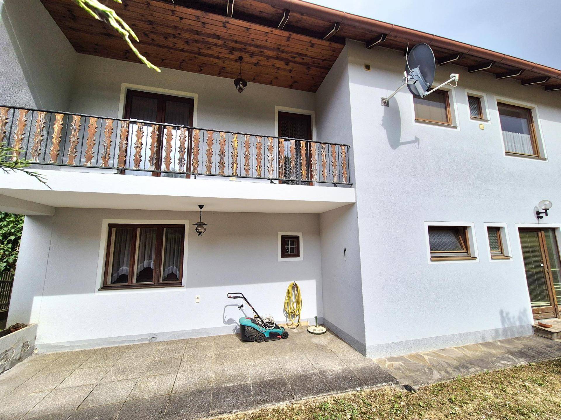Rückseite des Hauses mit einer gepflasterten Terrasse im Erdgeschoss und einem Balkon im Obergeschoss.