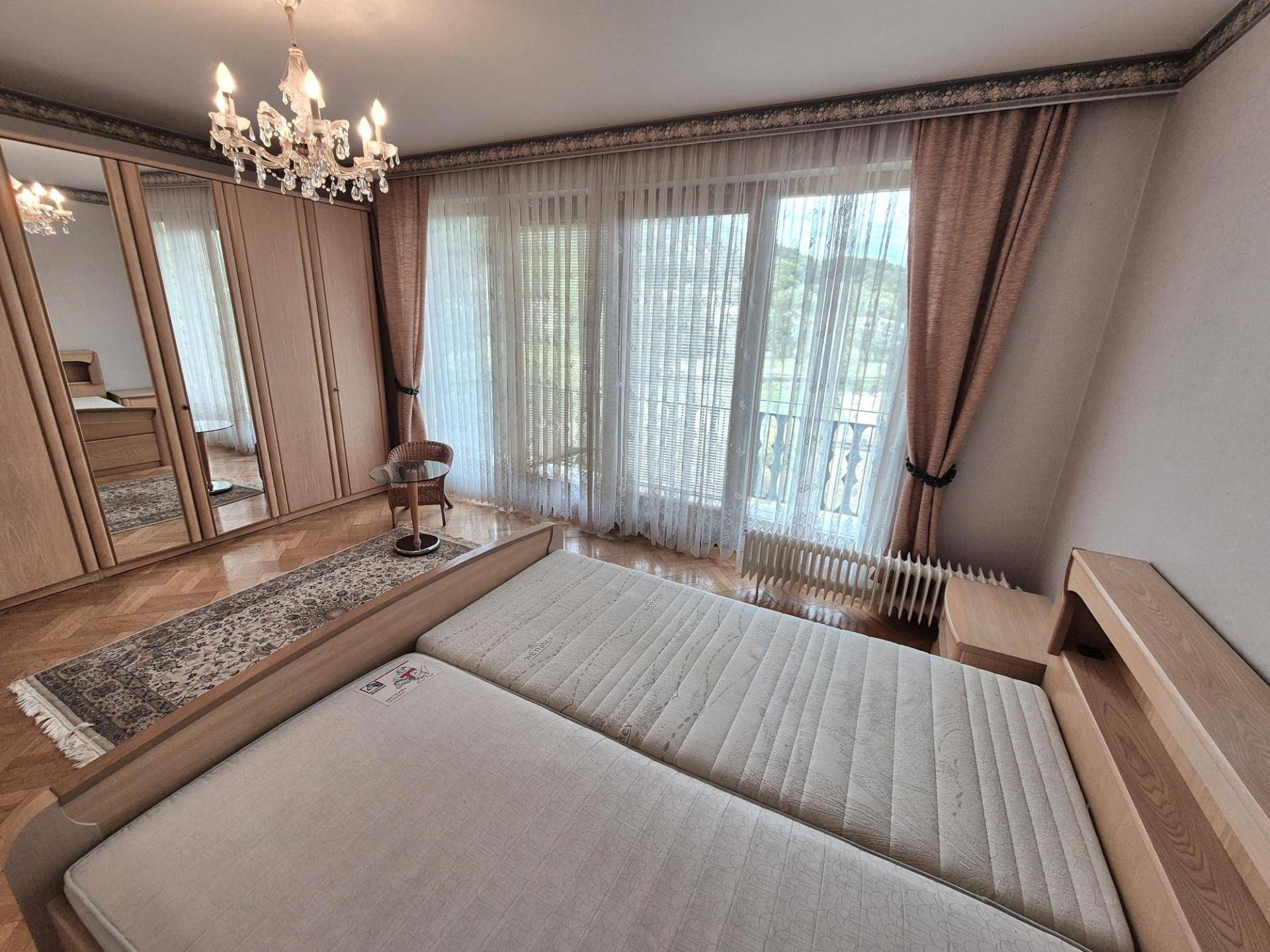 Schlafzimmer mit Doppelbett, Einbauschränken und großem Fenster mit Zugang zum Balkon.