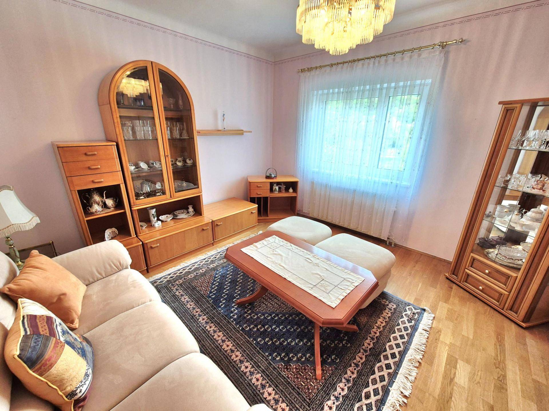 Gemütliches Wohnzimmer mit traditionellen Holzmöbeln, einem Sofa und einem großen Teppich.