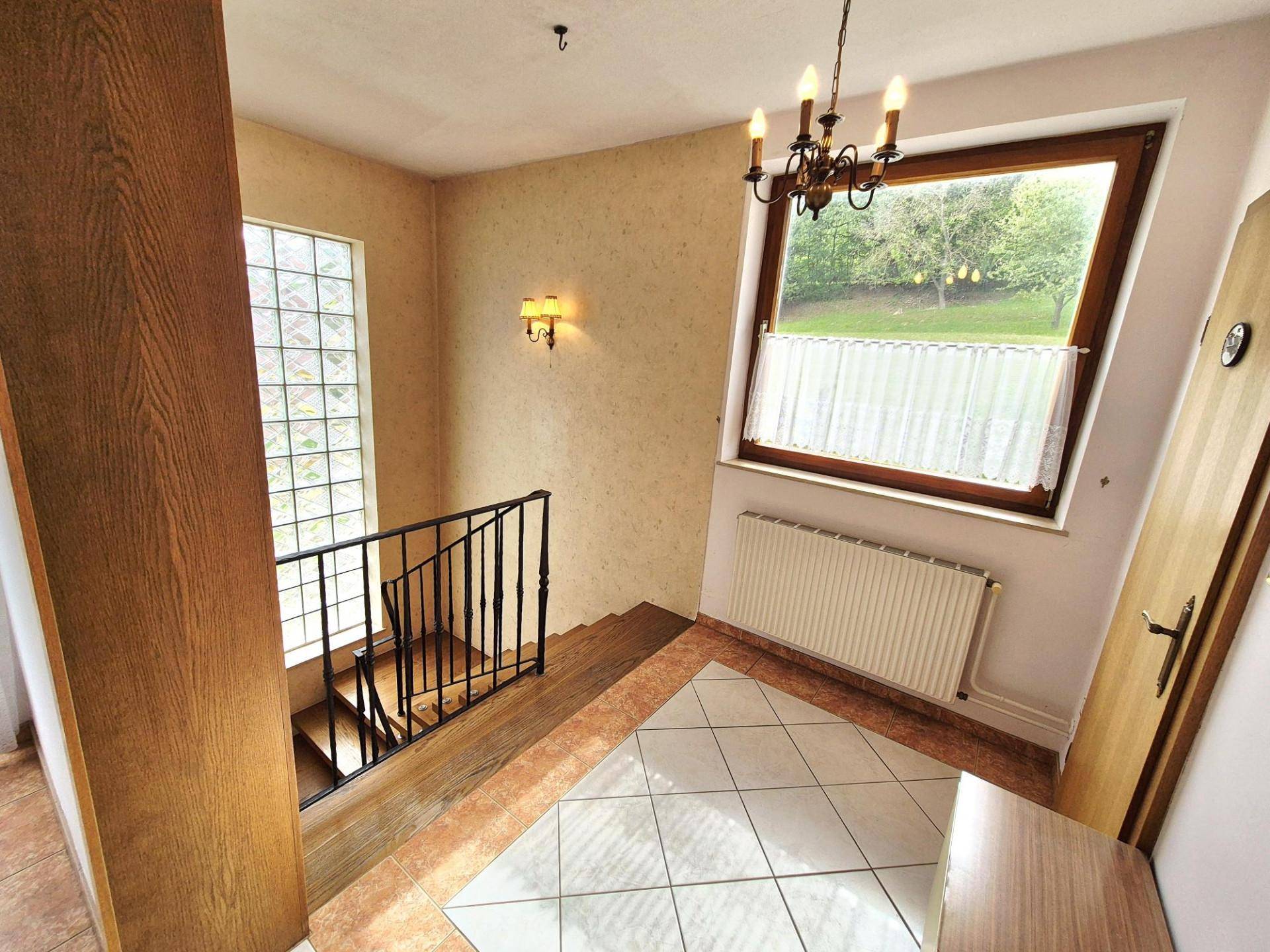 Heller Treppenabsatz mit Holztreppe, großem Fenster und einem Glasbausteinfenster.