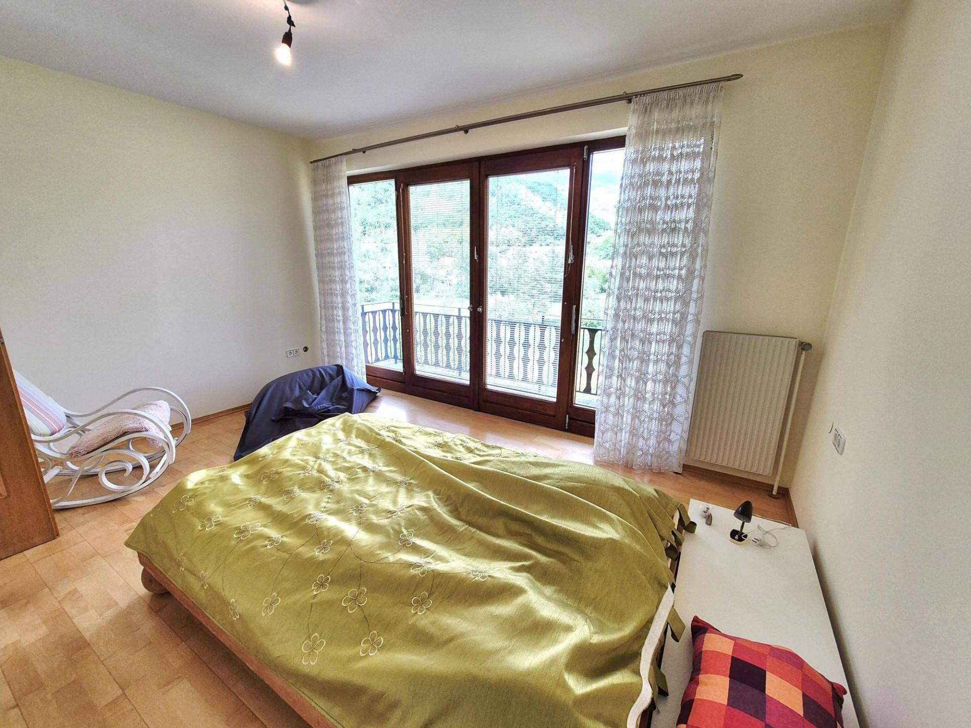 Schlafzimmer mit Doppelbett und einer großen Glastür, die zu einem französischen Balkon führt.