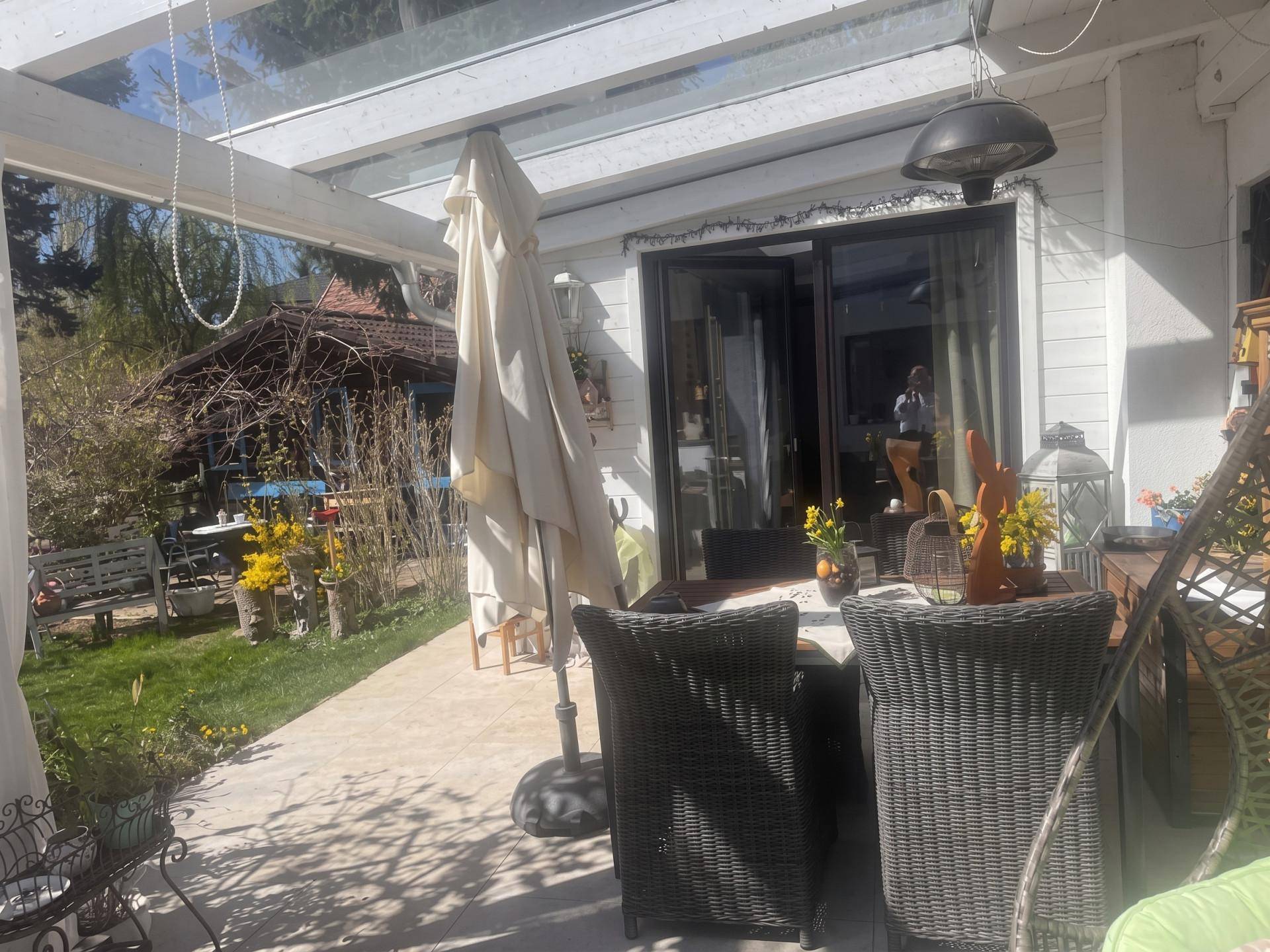 Überdachte Terrasse mit Gartenmöbeln und Blick auf den grünen Gartenbereich.