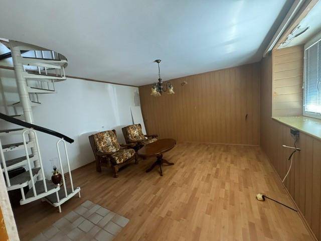 Wohnbereich mit Holzvertäfelung, Laminatboden und einer Wendeltreppe, die in ein Obergeschoss führt.