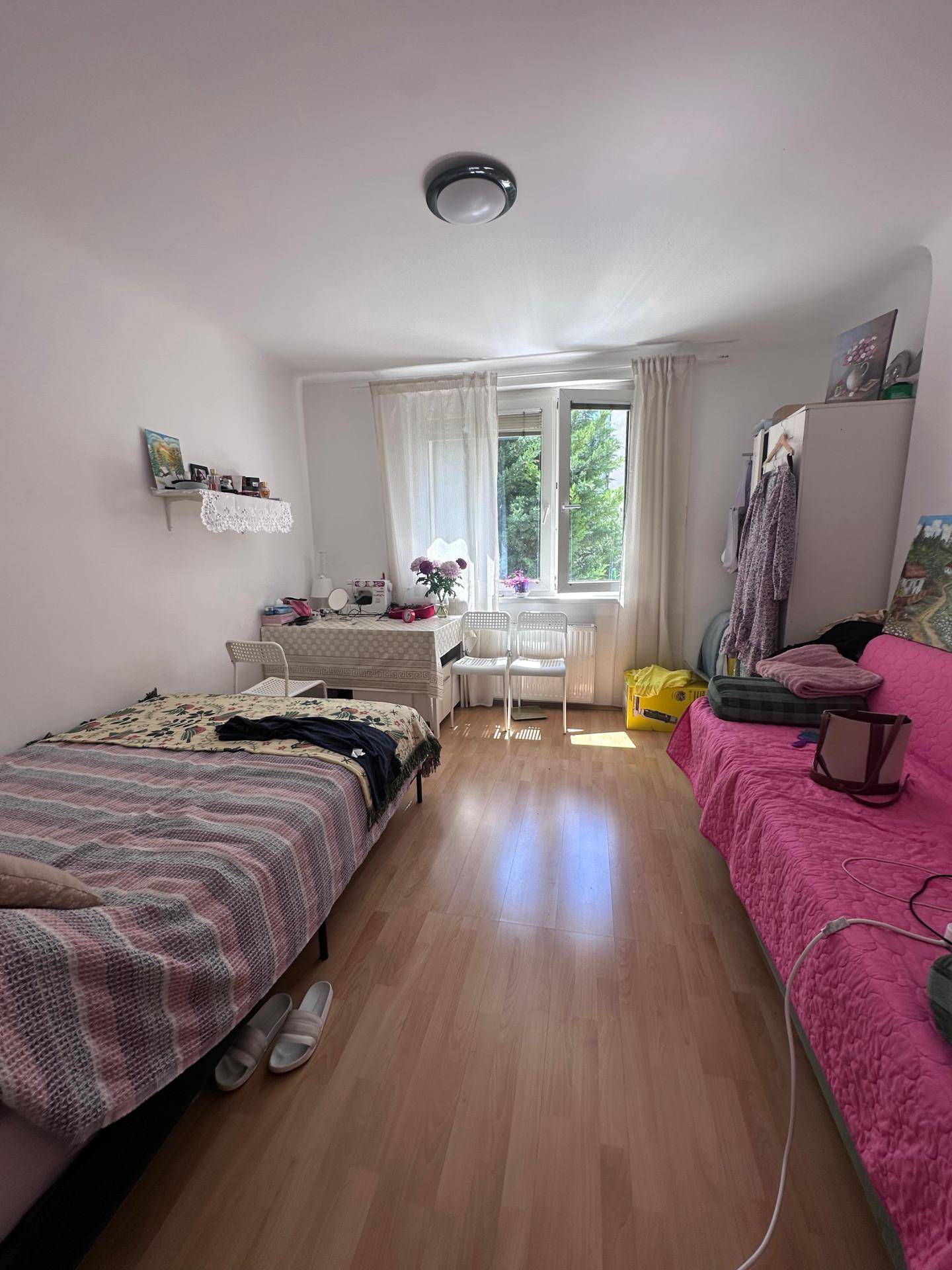 Helles Schlafzimmer mit Einzelbett, Sofa und Holzboden.