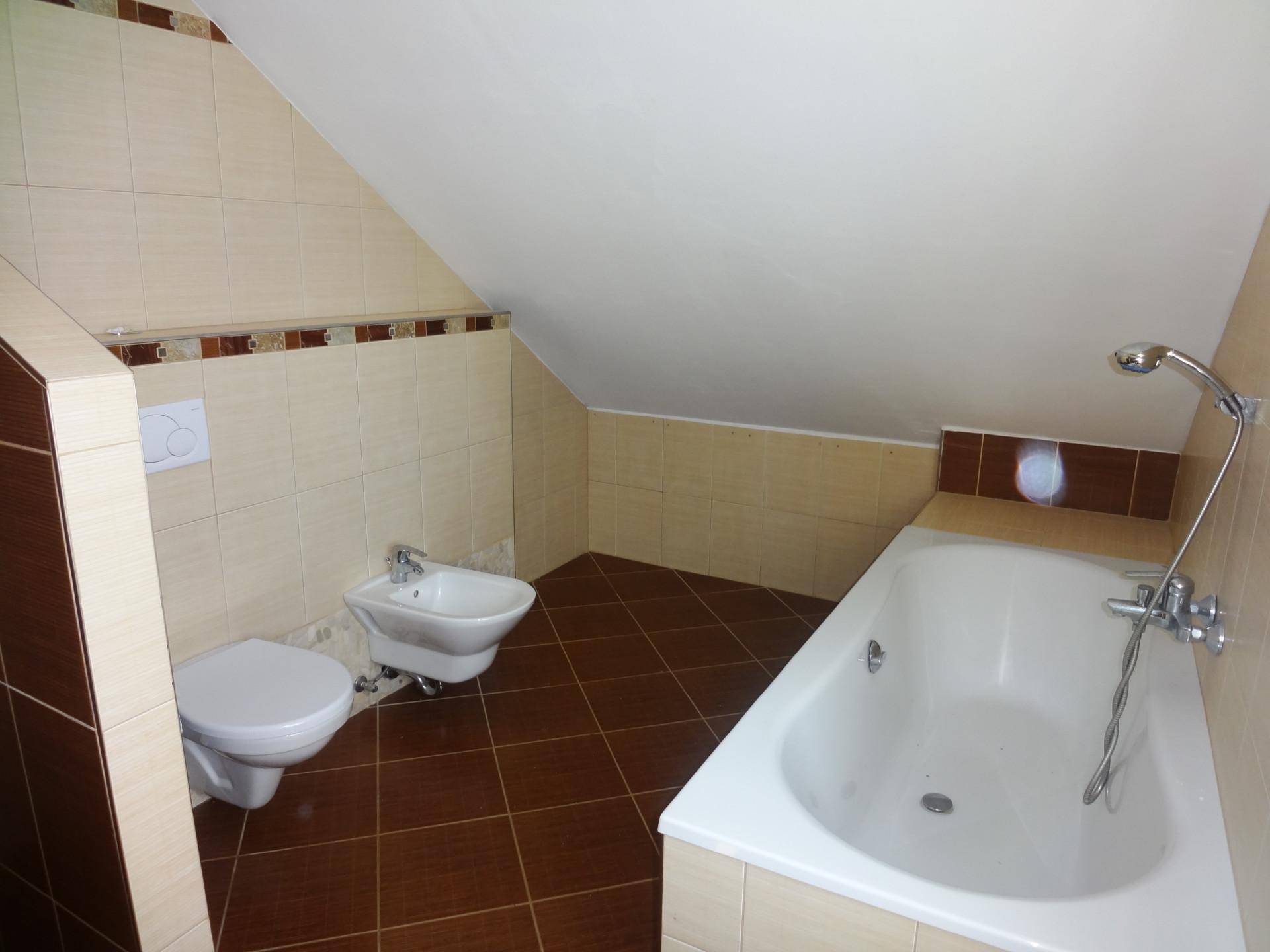 Badezimmer im Dachgeschoss mit Badewanne, WC, Bidet und Fliesen in Braun-Beige.