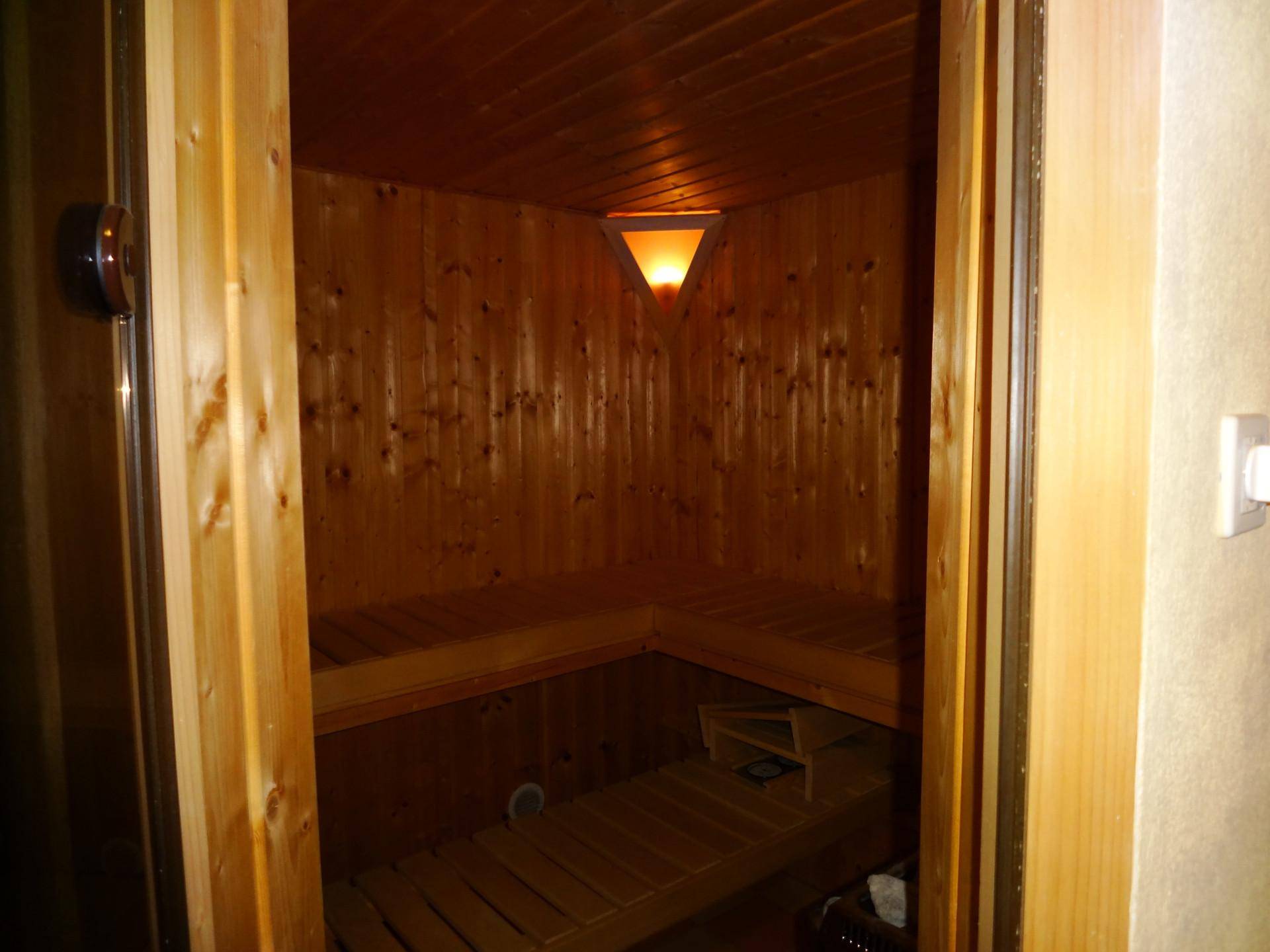 Holzvertäfelte Sauna mit Sitzbänken und stimmungsvoller Beleuchtung für Entspannung.