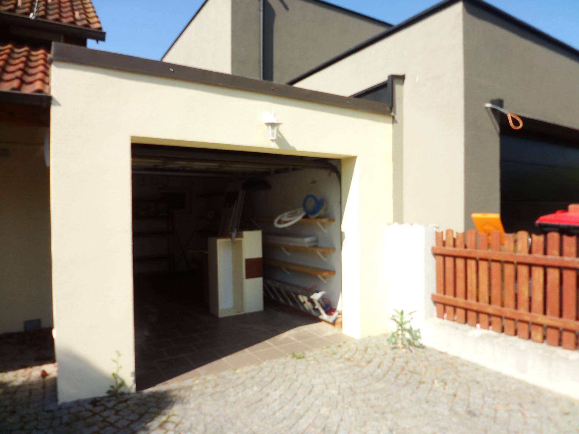 Offene Garage mit Stauraum und einer gepflasterten Zufahrt.