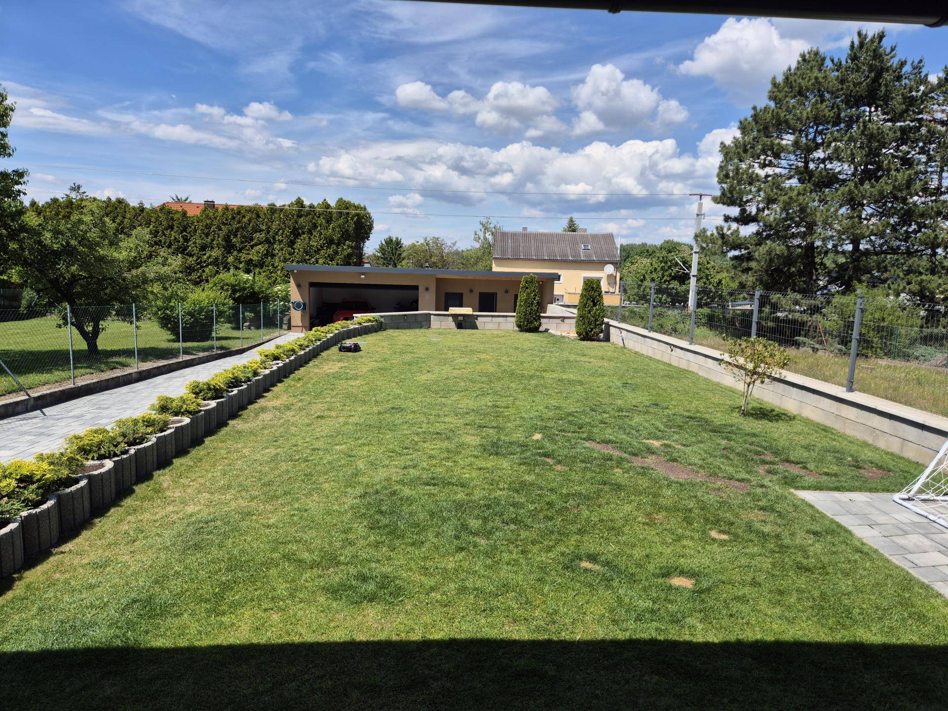 Weitläufiger, gepflegter Gartenbereich mit Rasenfläche und separatem Garagengebäude im Hintergrund.