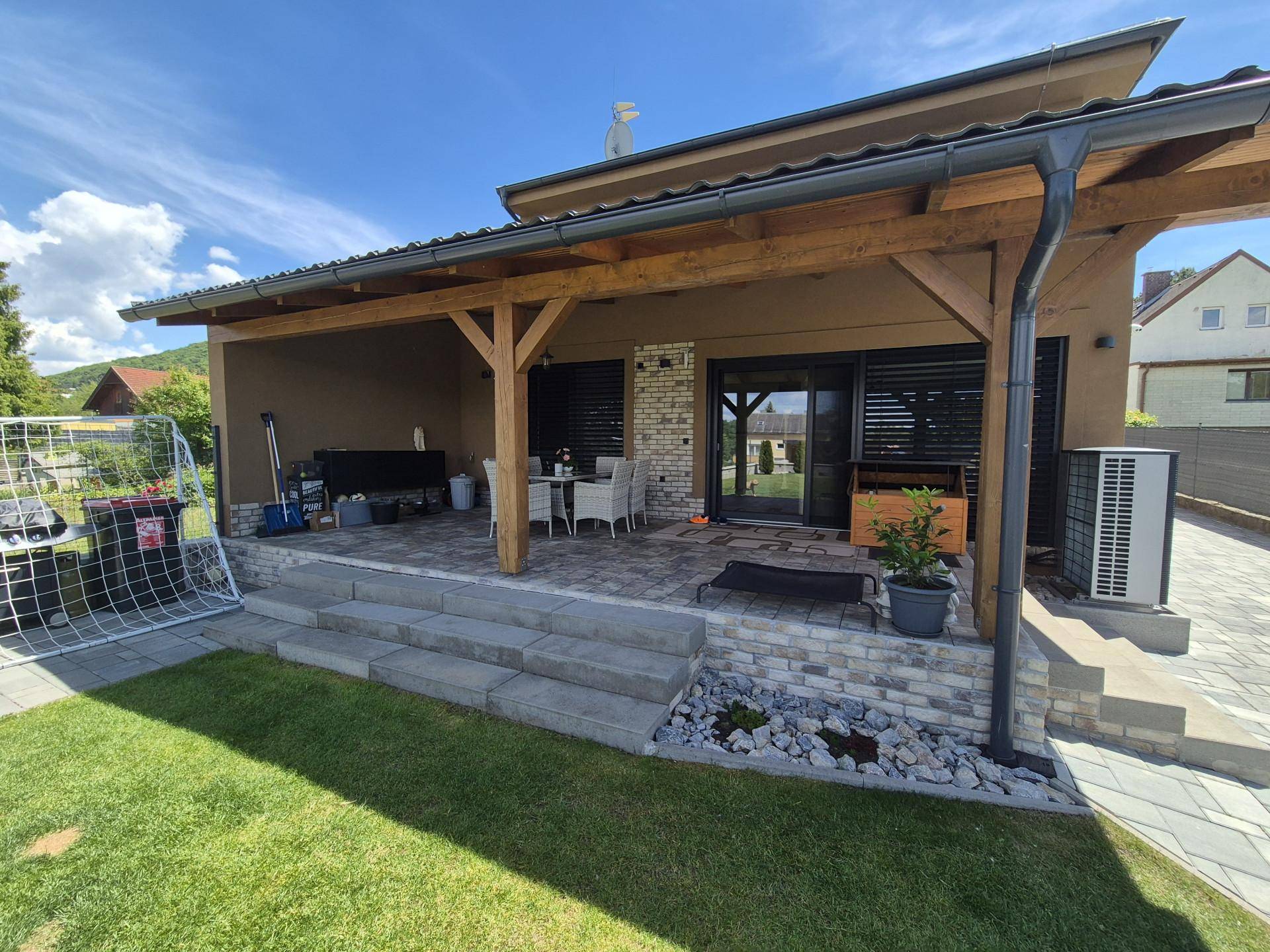 Überdachte Terrasse mit Steinpflaster und Zugang zum Garten, ideal für entspannte Stunden.