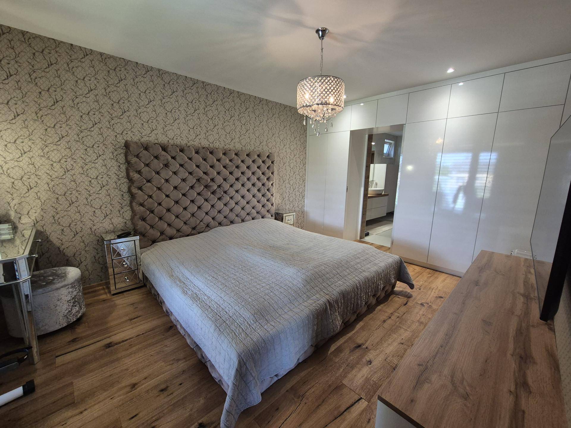 Geräumiges Schlafzimmer mit Holzboden, großem Bett und elegantem Spiegelschrank.