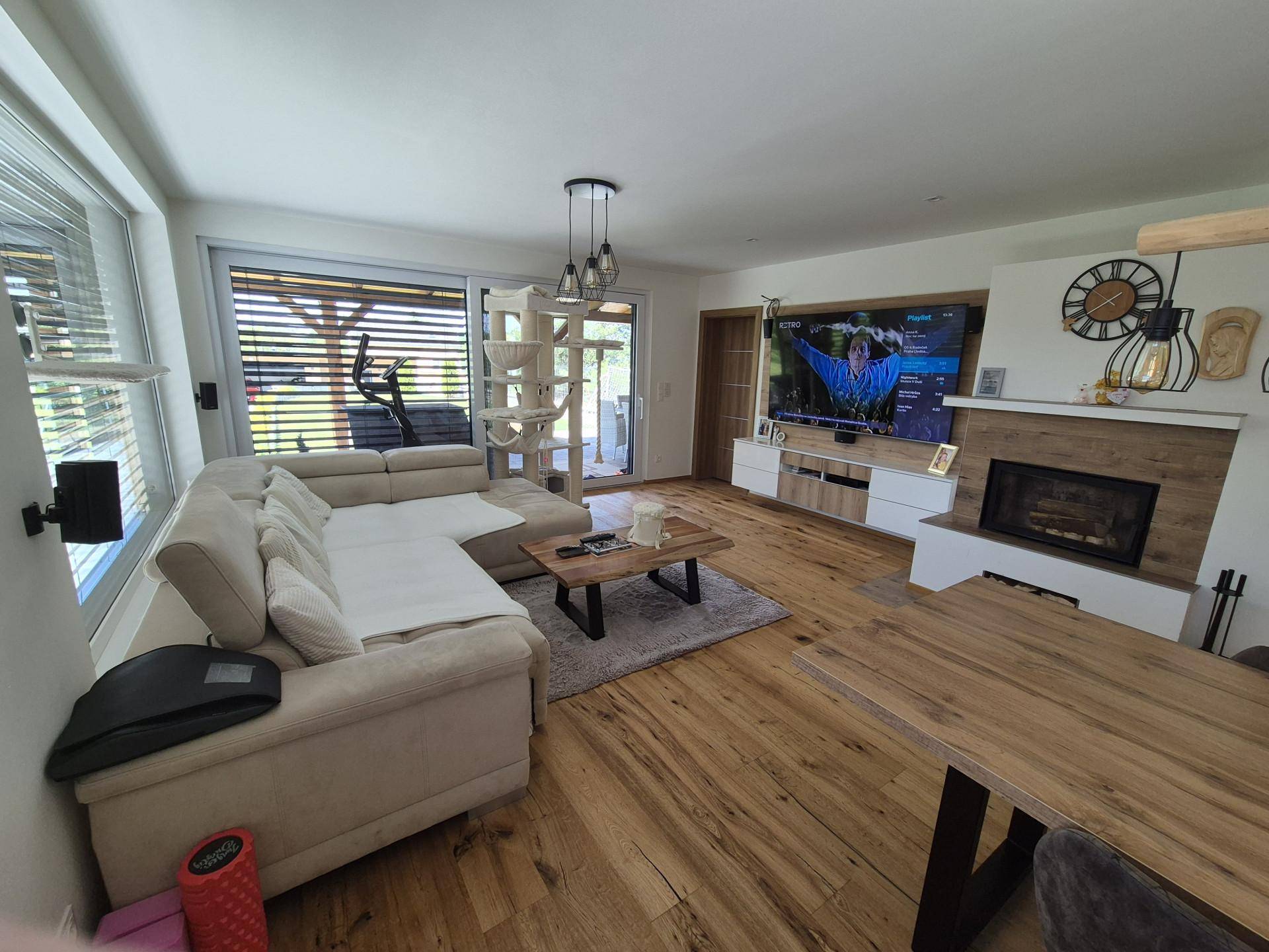 Heller Wohn- und Essbereich mit Holzboden, großem Sofa und modernem Kamin.