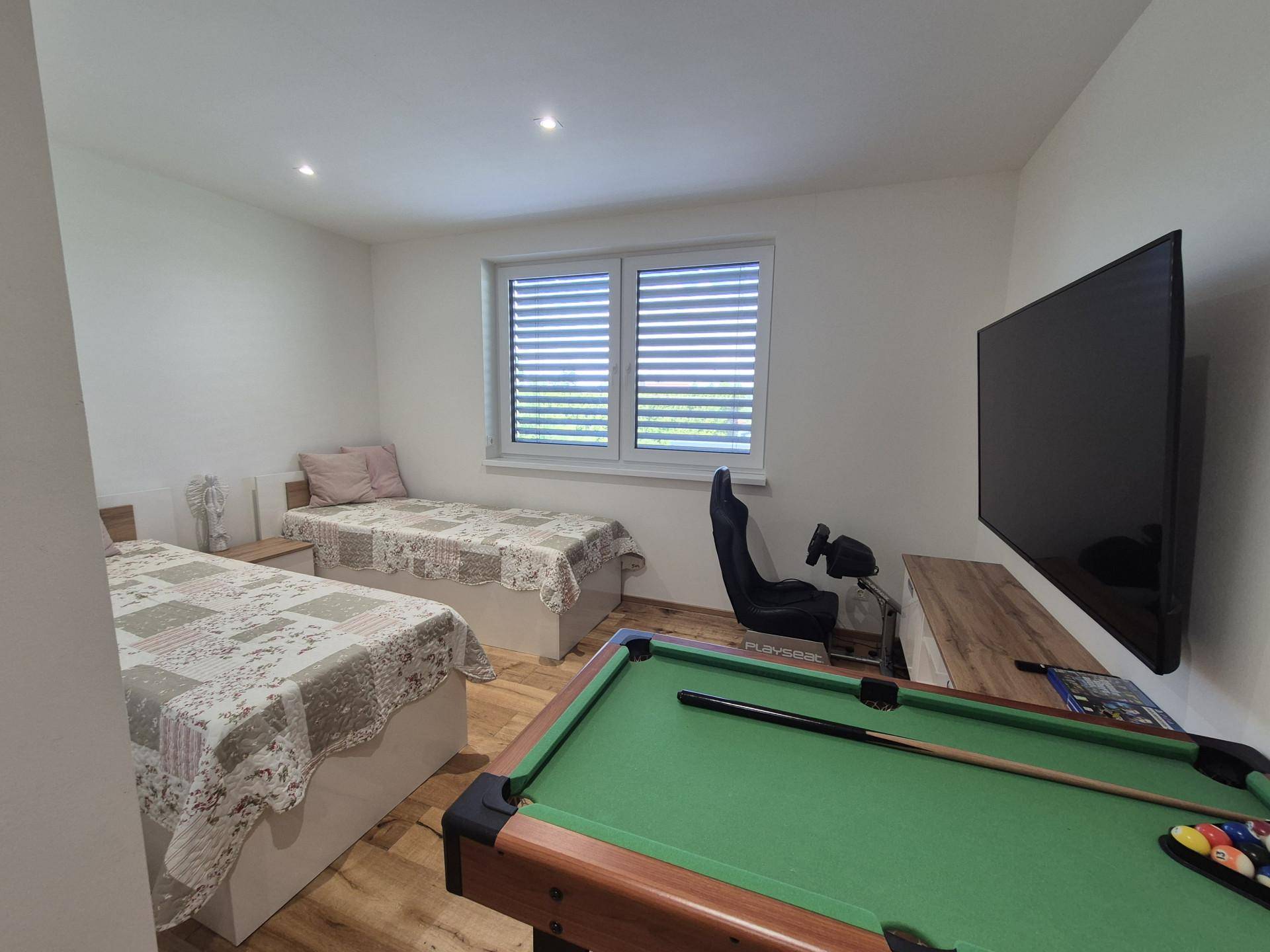 Gästezimmer mit zwei Einzelbetten, Billardtisch und großem Fernseher.