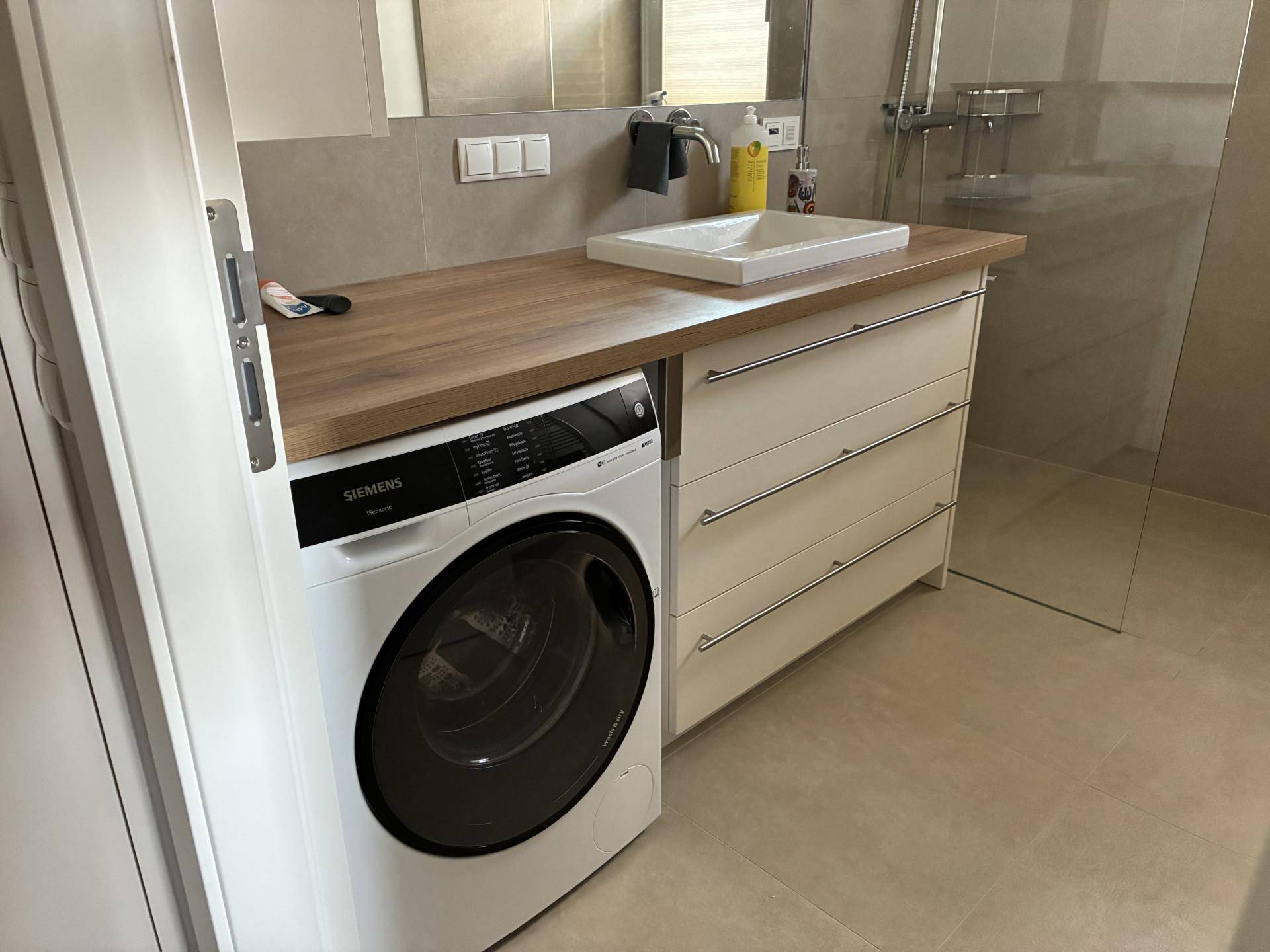 Modernes Badezimmer mit Einzelwaschbecken, Holzwaschtisch und integrierter Waschmaschine.